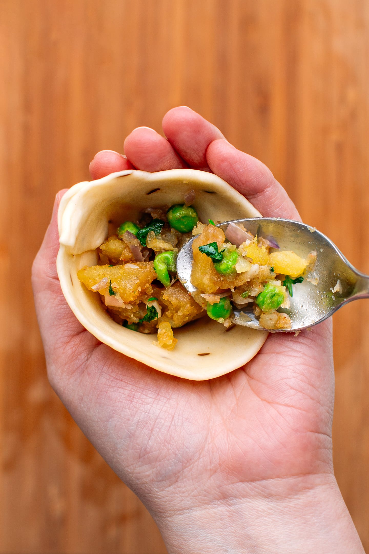 Filling a samosa wrapper with potatoes.