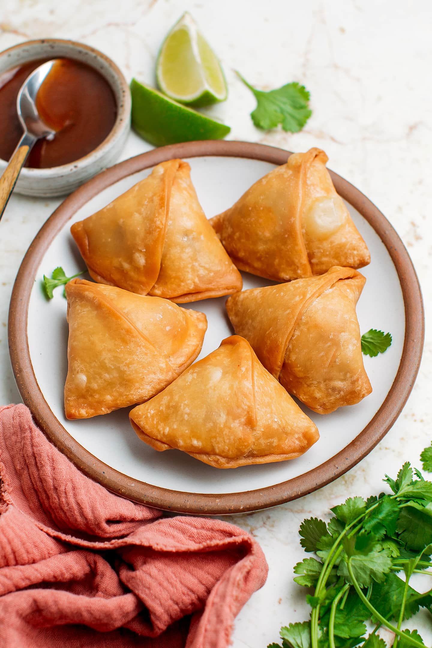 Five samosas on a small plate.