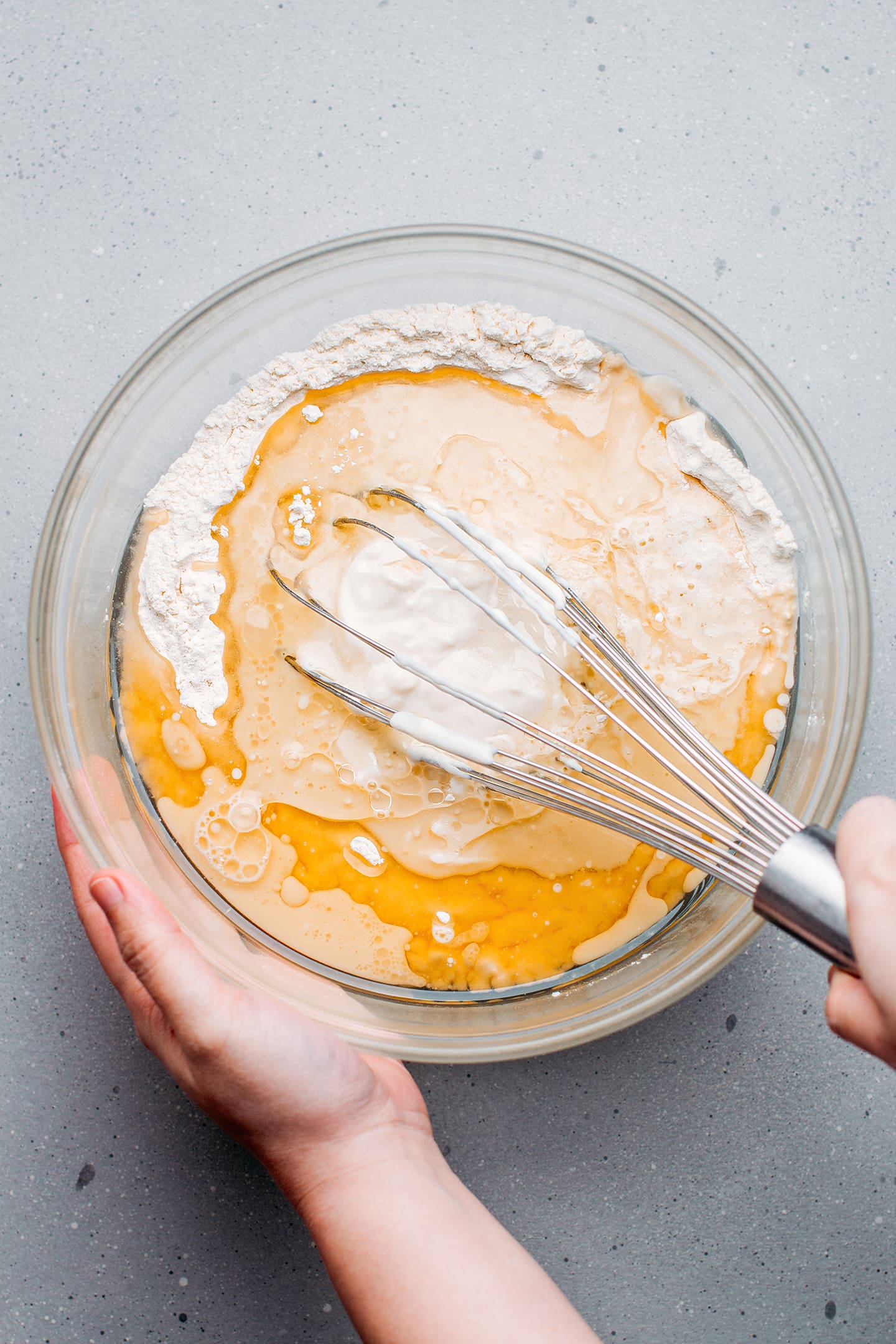 Whisking flour with yogurt and oil in a mixing bowl.