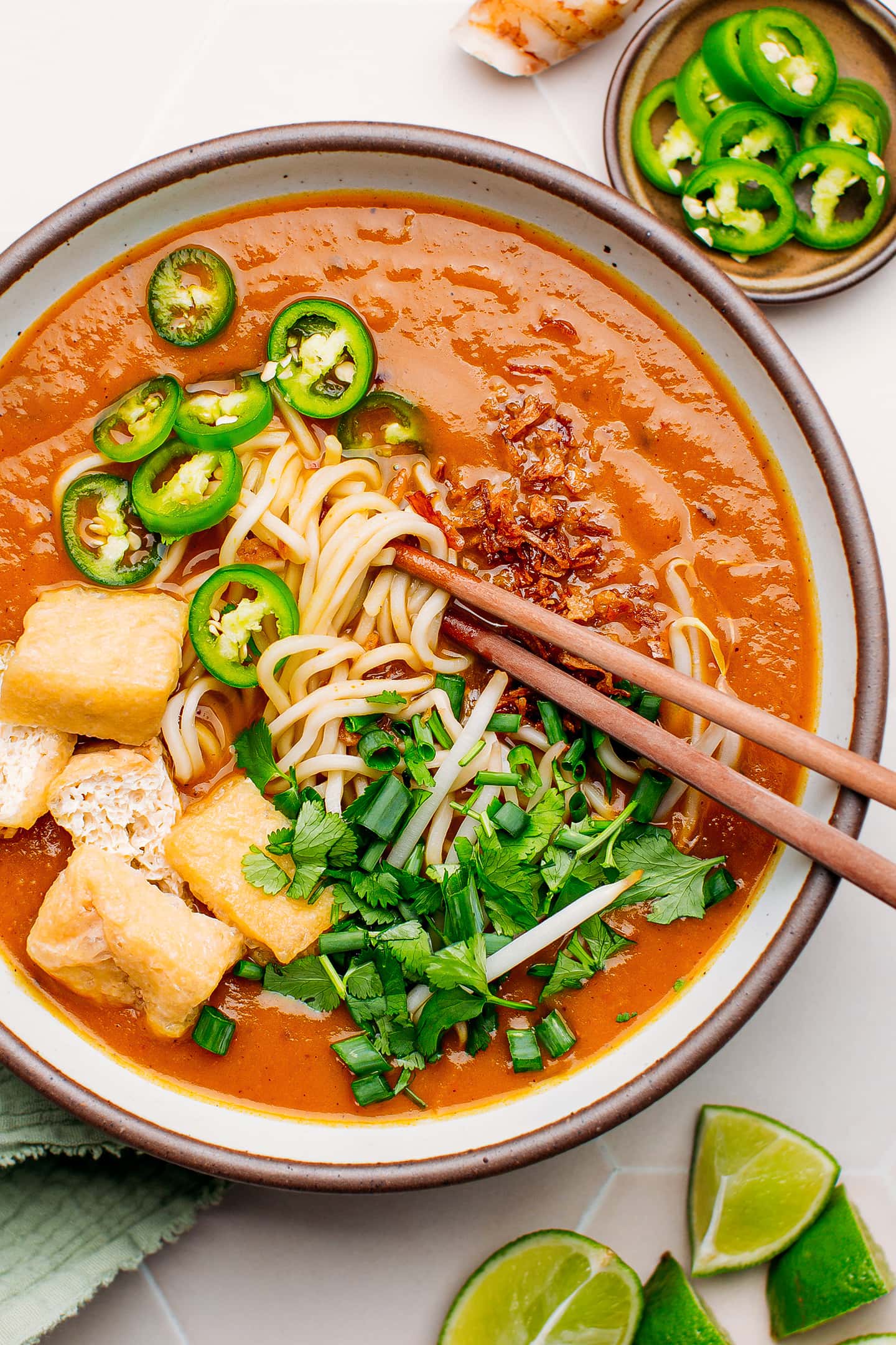 Close-up of sweet potato gravy topped with noodles, fresh herbs, and mung bean sprouts.