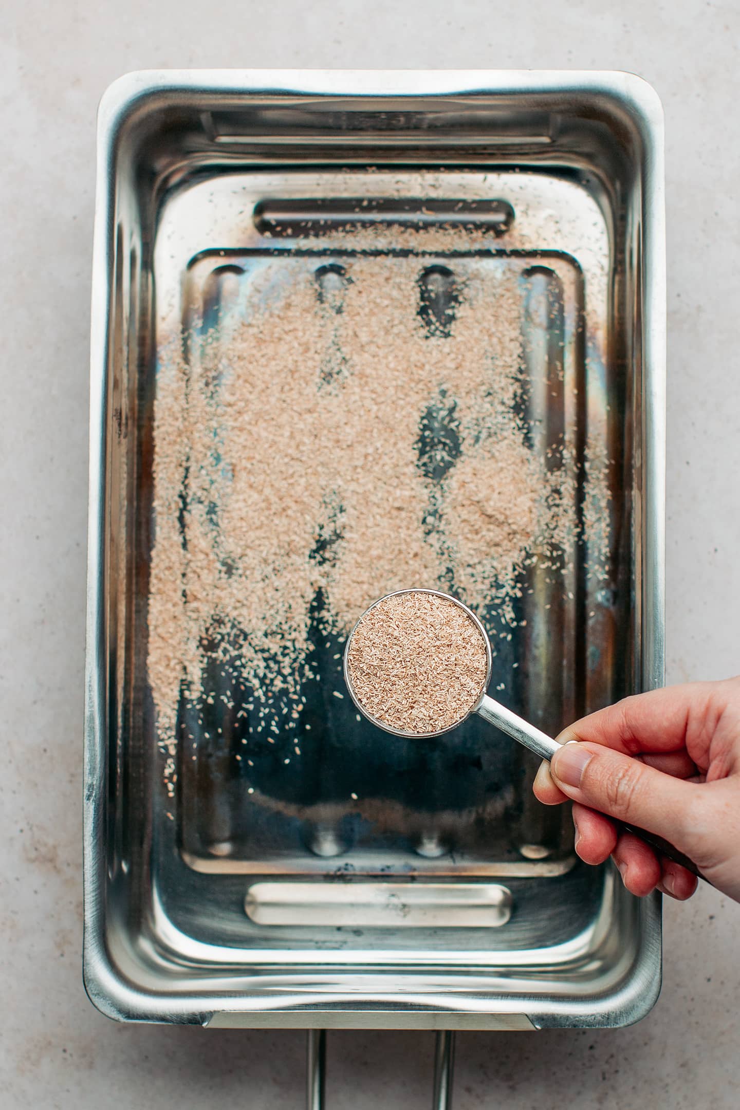 Sprinkling wood chips in a stovetop smoker.