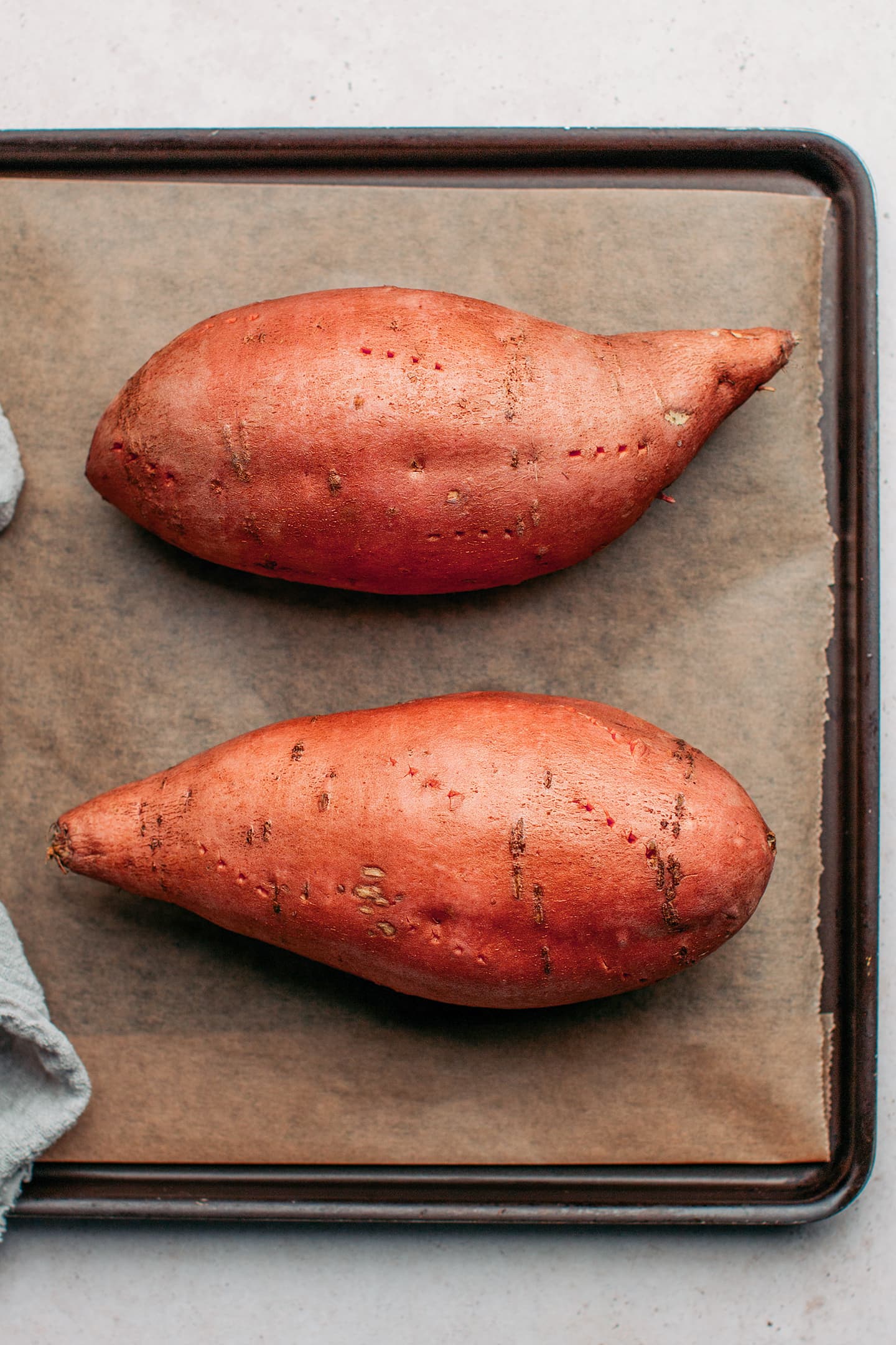 Unbaked sweet potatoes on a baking sheet.