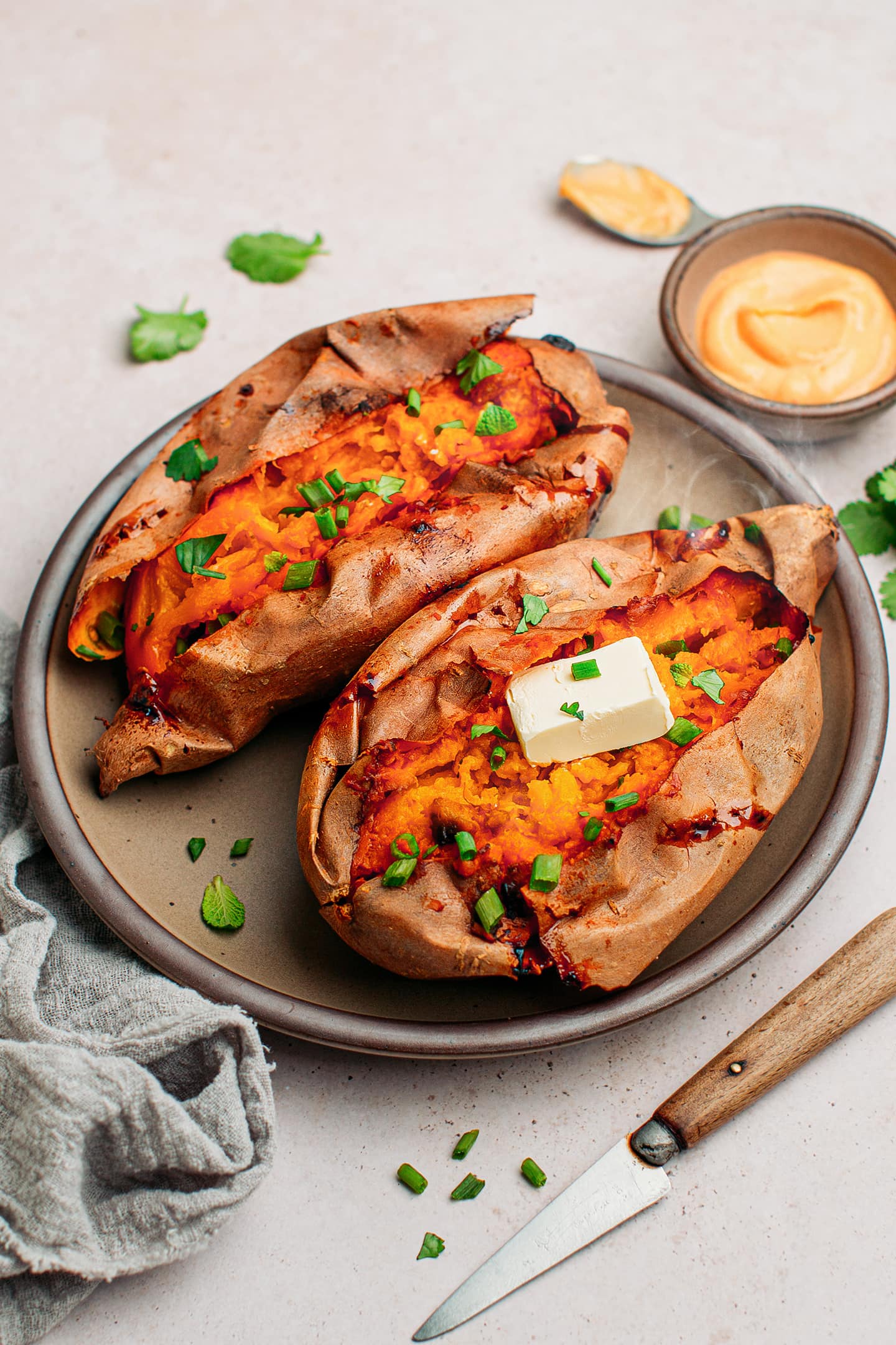 Smoked sweet potatoes topped with green onions and butter.