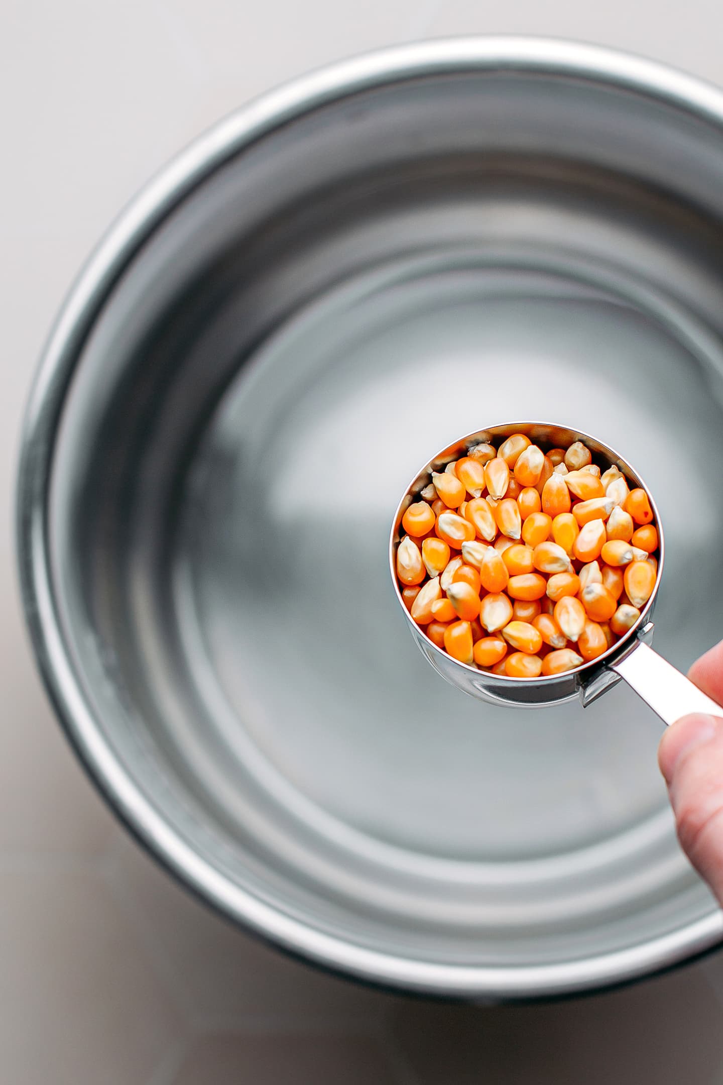 Adding popcorn kernels to a pot.