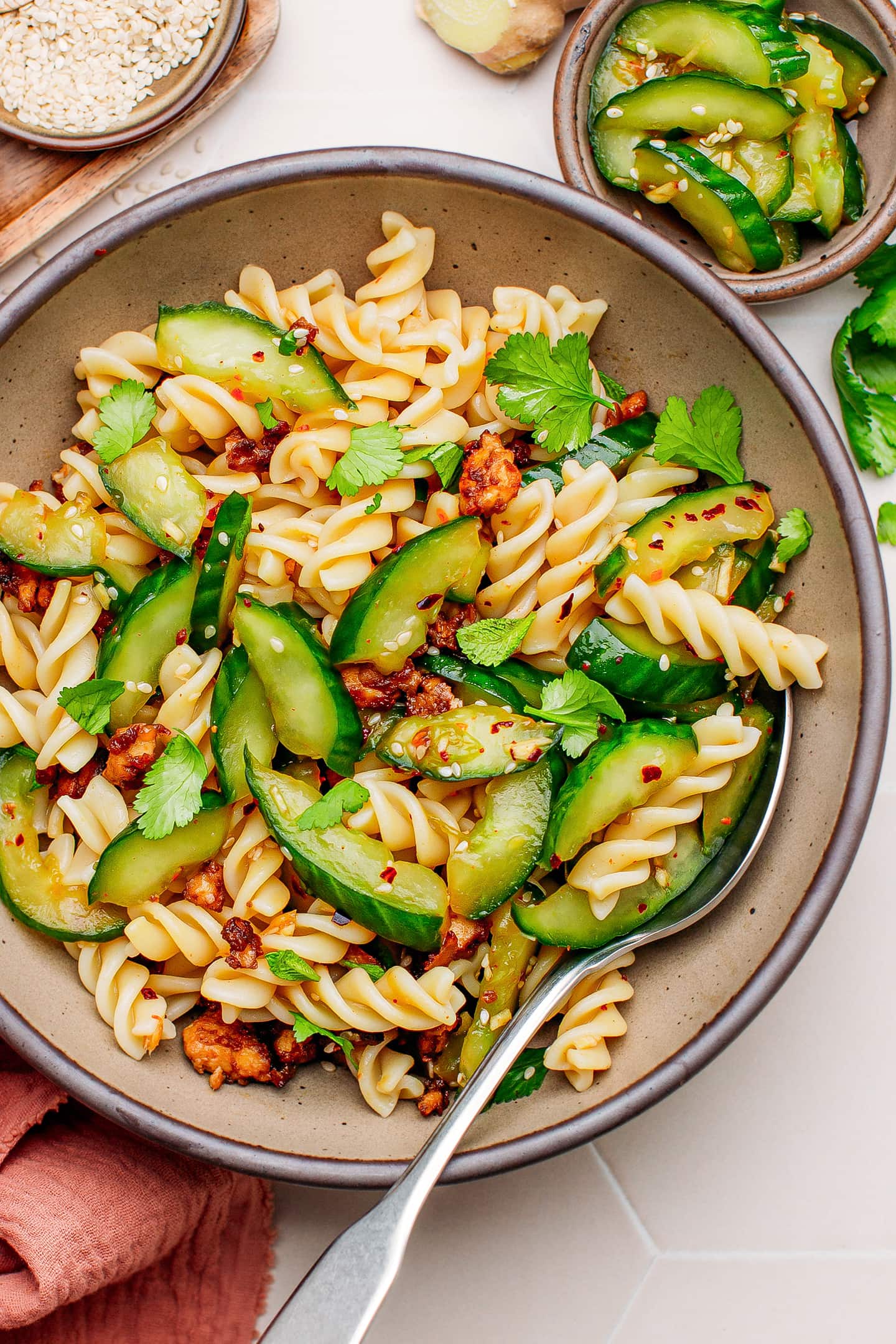 Cucumber salad with fusilli, tofu, and sesame seeds in a bowl.