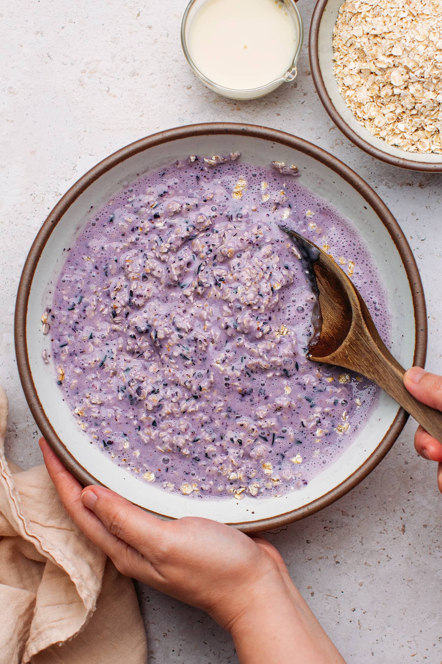 Stirring blended blueberries with quick oats in a bowl.