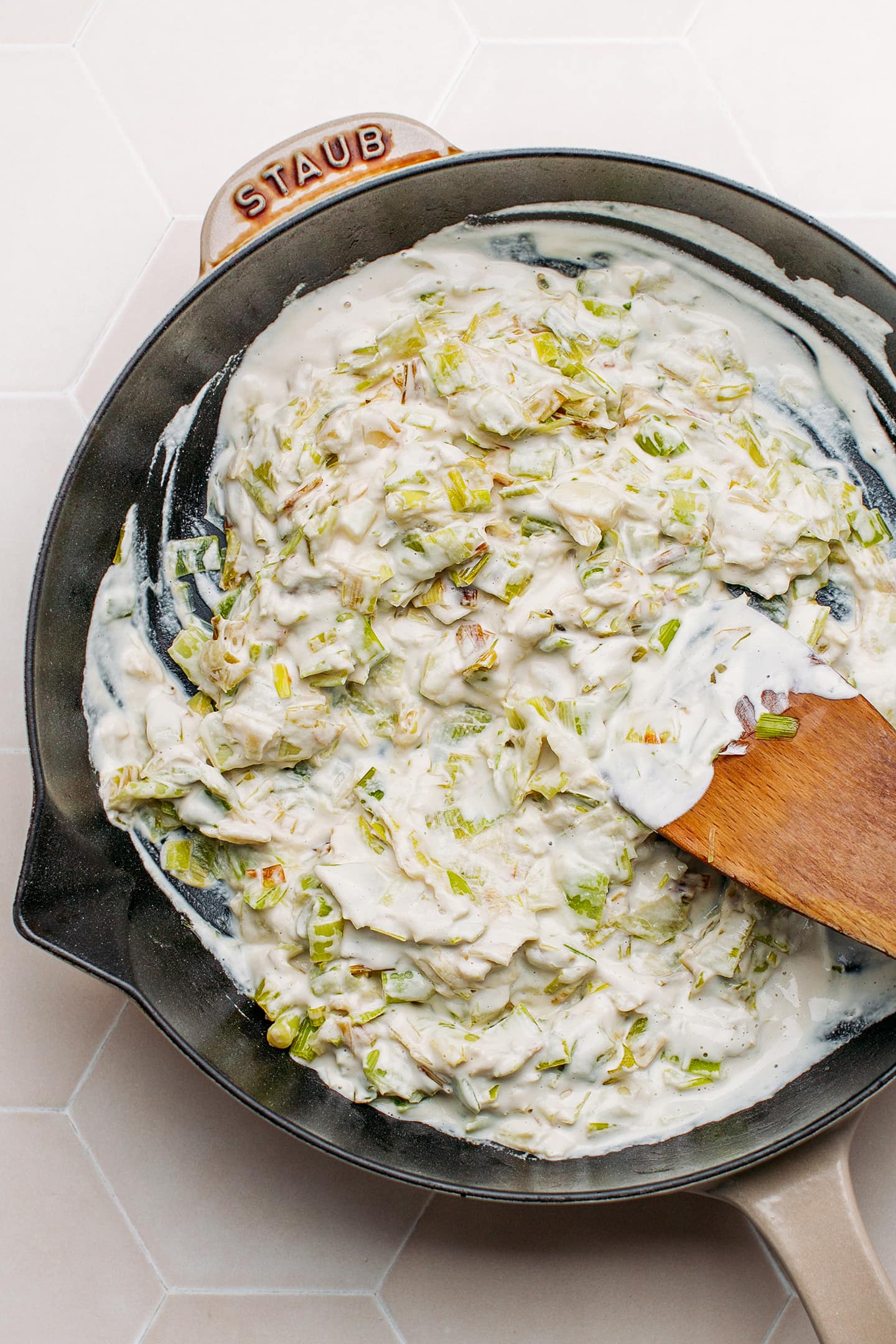 Sautéed leeks coated with cashew cream in a pan.