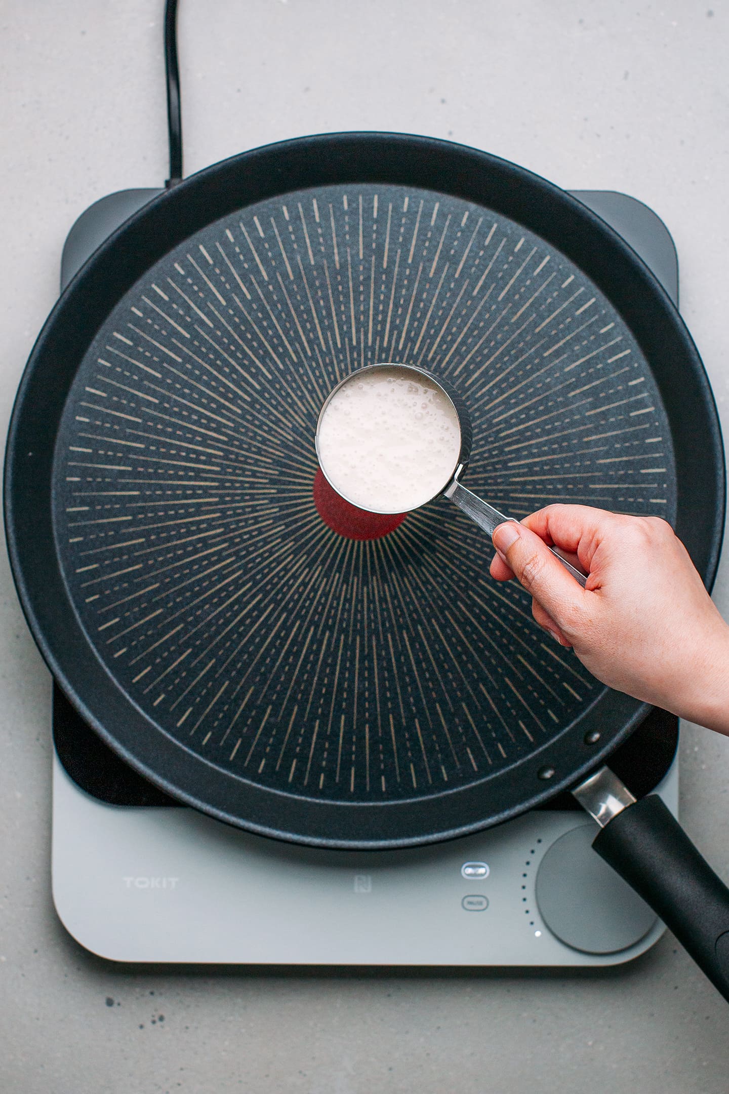 Pouring rice flour batter on a pan.