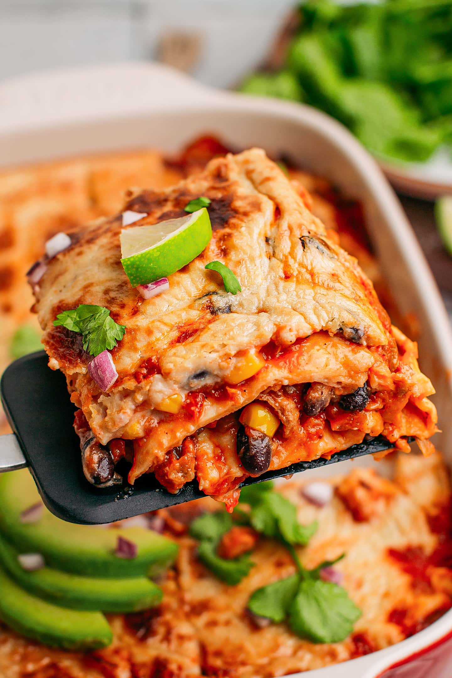 Close-up of a portion of enchilada casserole topped with lime and cilantro.