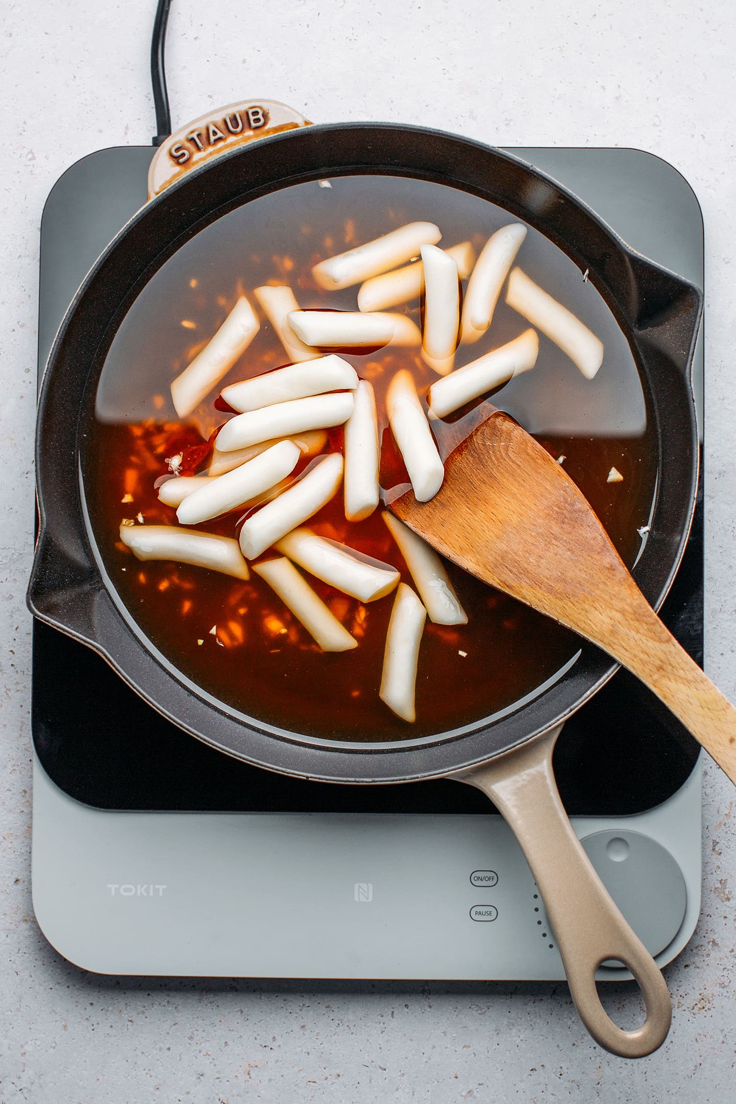 Rice cakes and gochujang paste in a skillet.