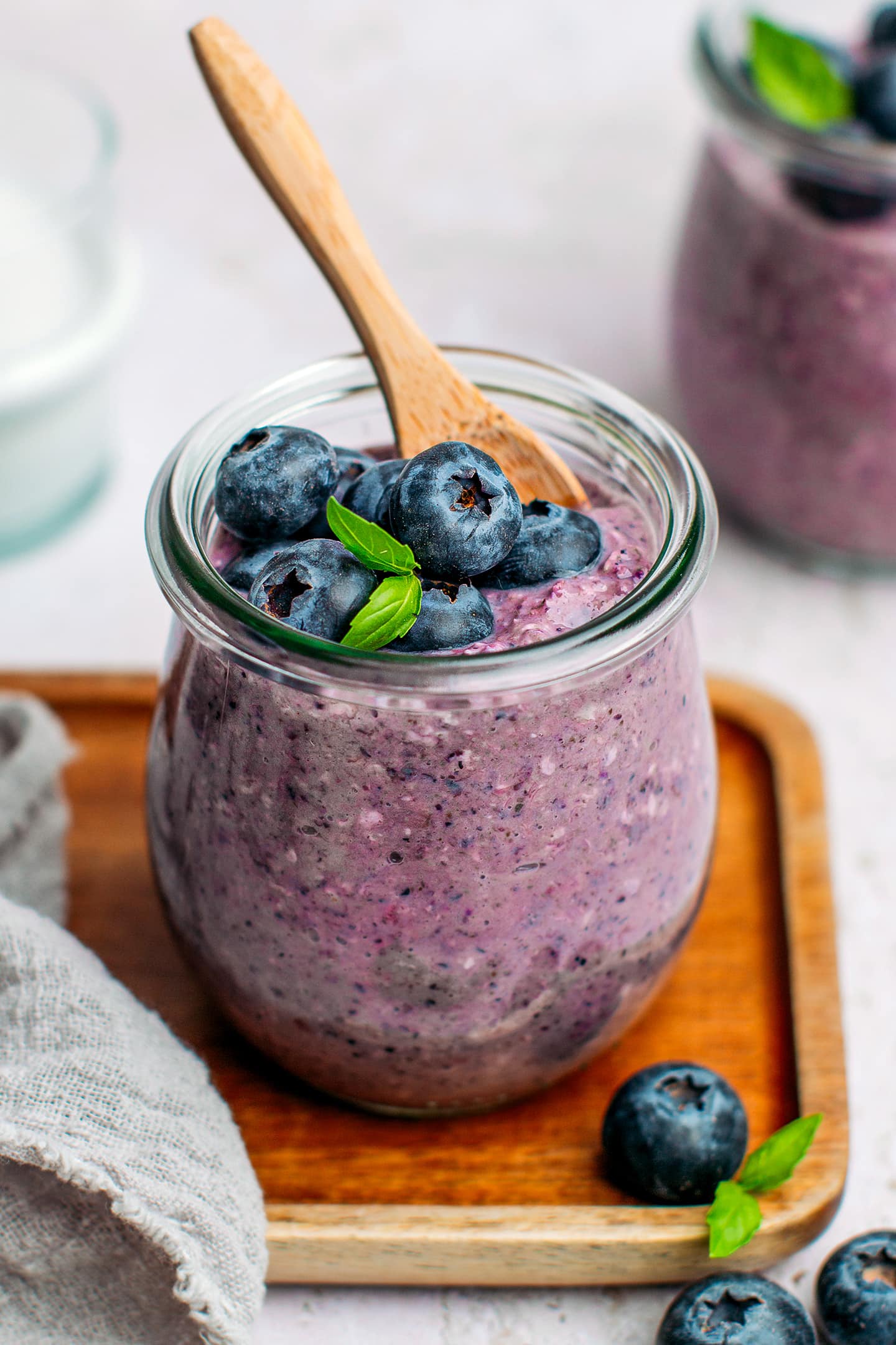 Blueberry oats with fresh blueberries and basil leaves in a small jar.