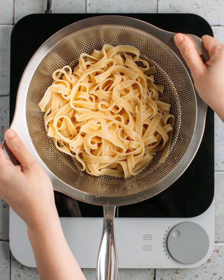 Draining cooked pasta using a colander.
