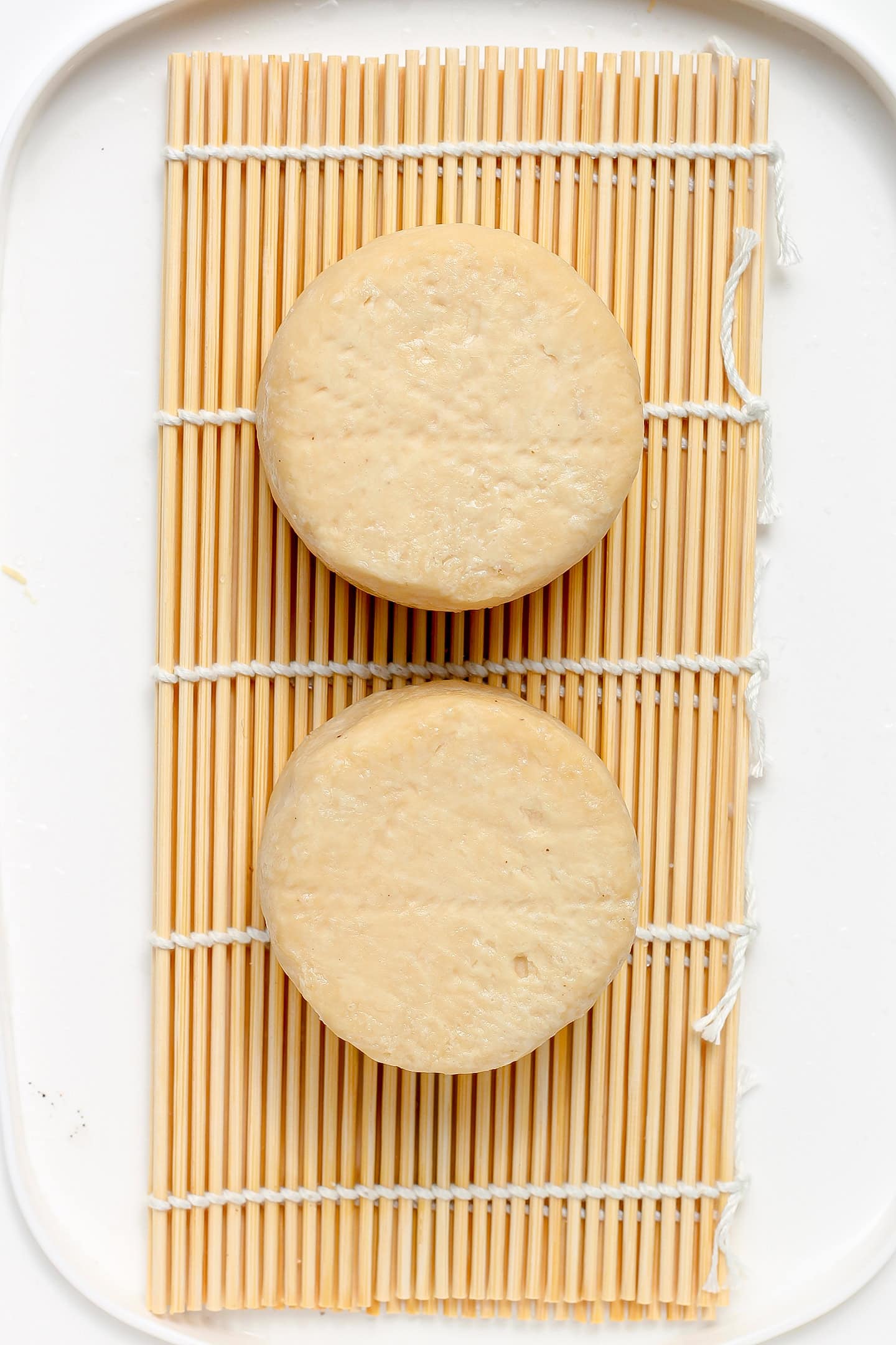 Two cashew cheeses on a bamboo mat.