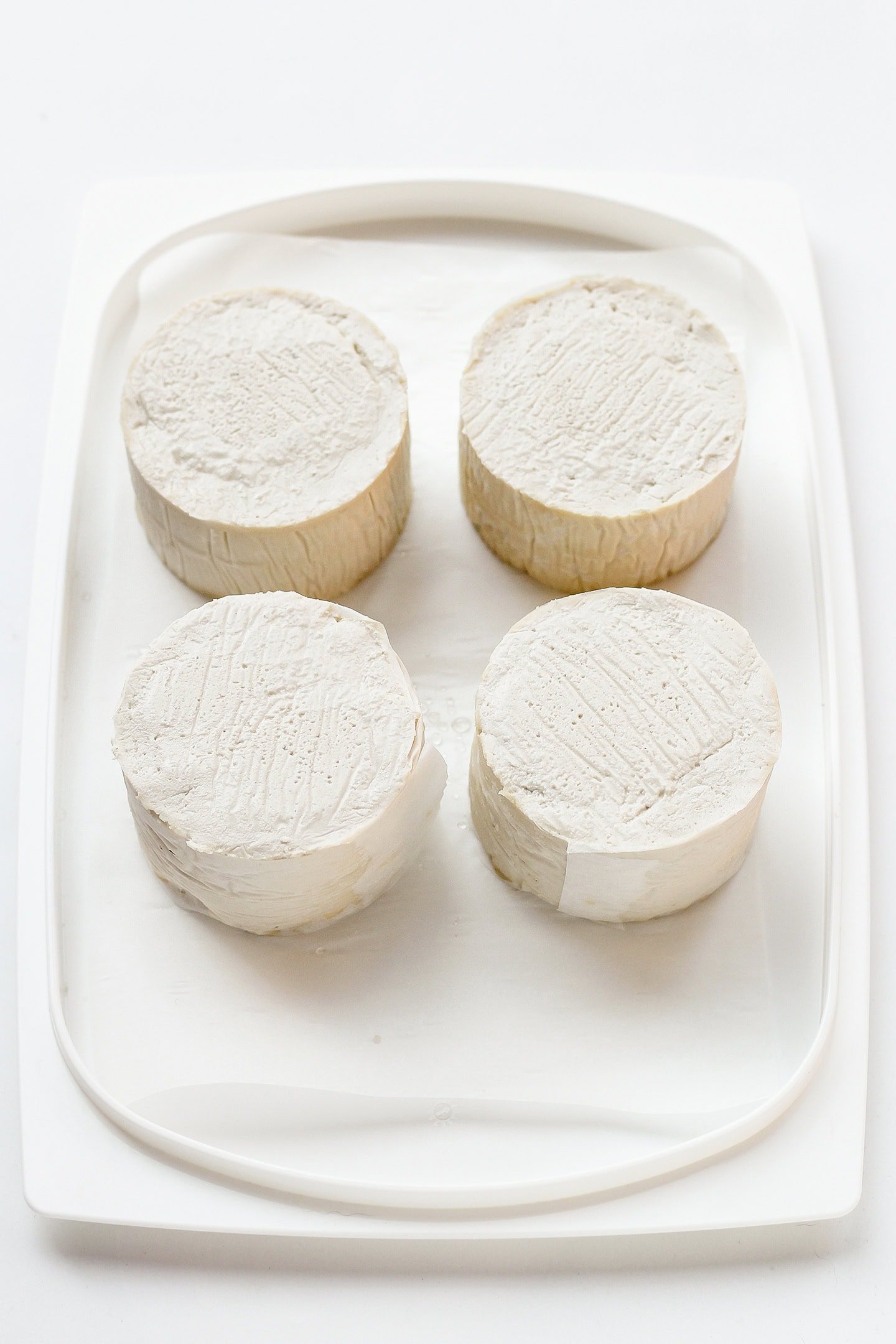 Four cashew cheeses on a plastic plate.