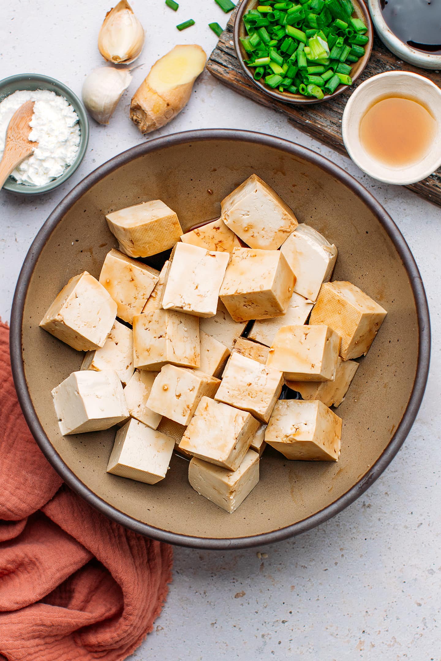 Cubed tofu tossed with soy sauce in a bowl.