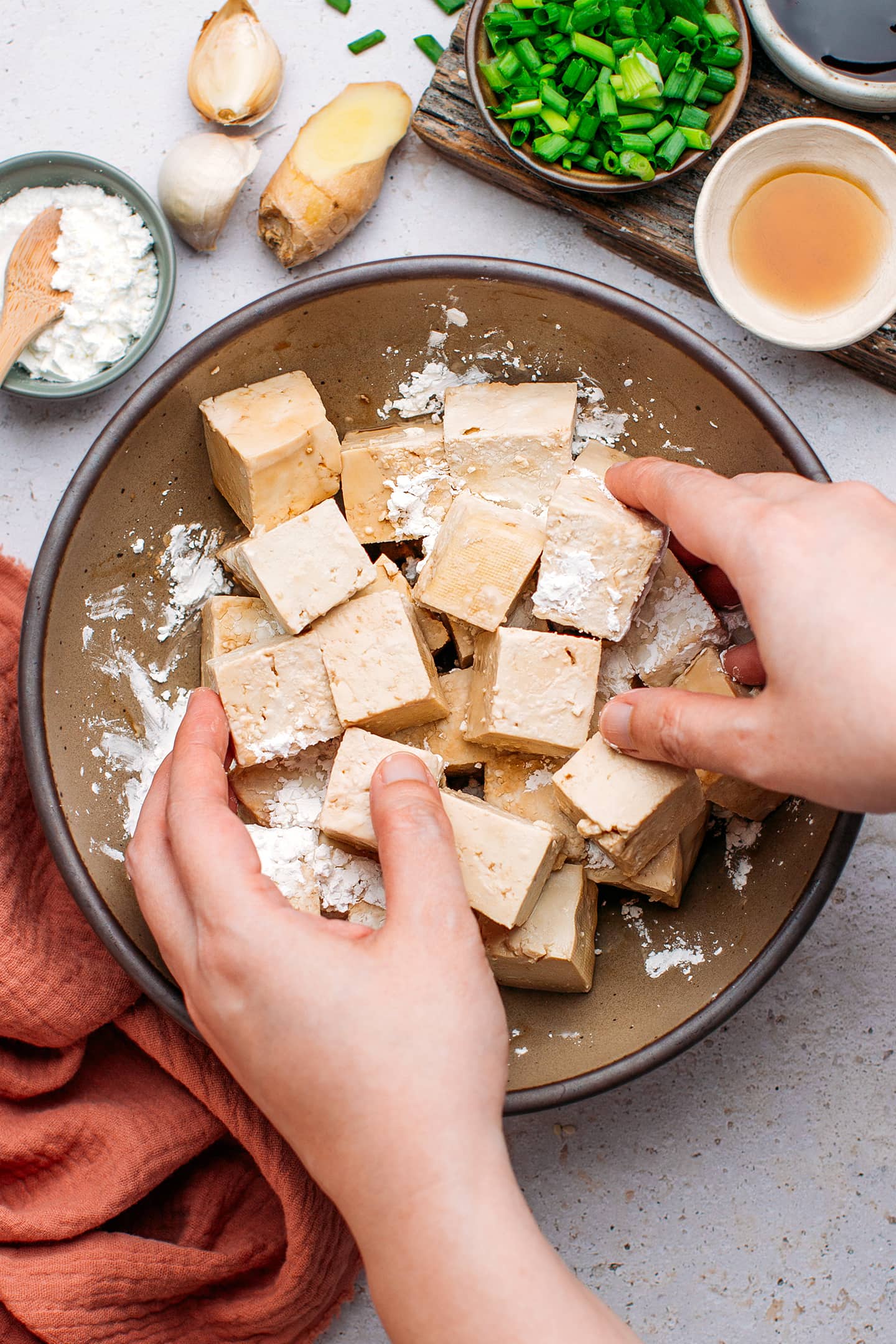 Tossing diced tofu with cornstarch.