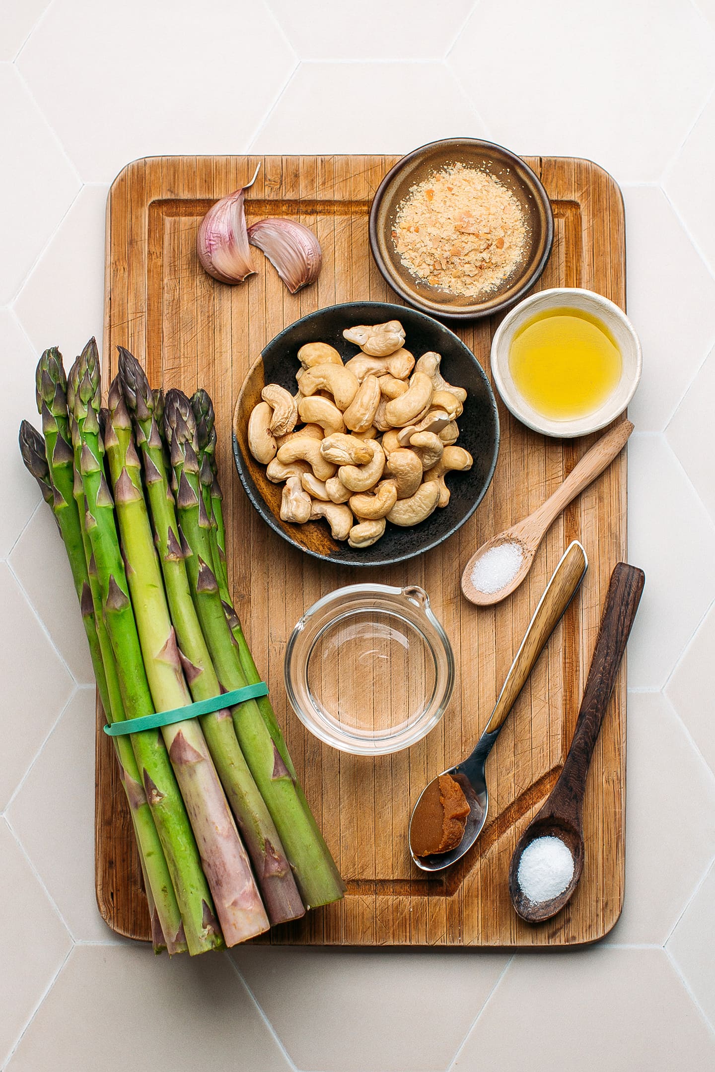 Ingredients like asparagus spears, raw cashews, garlic, olive oil, and nutritional yeast.