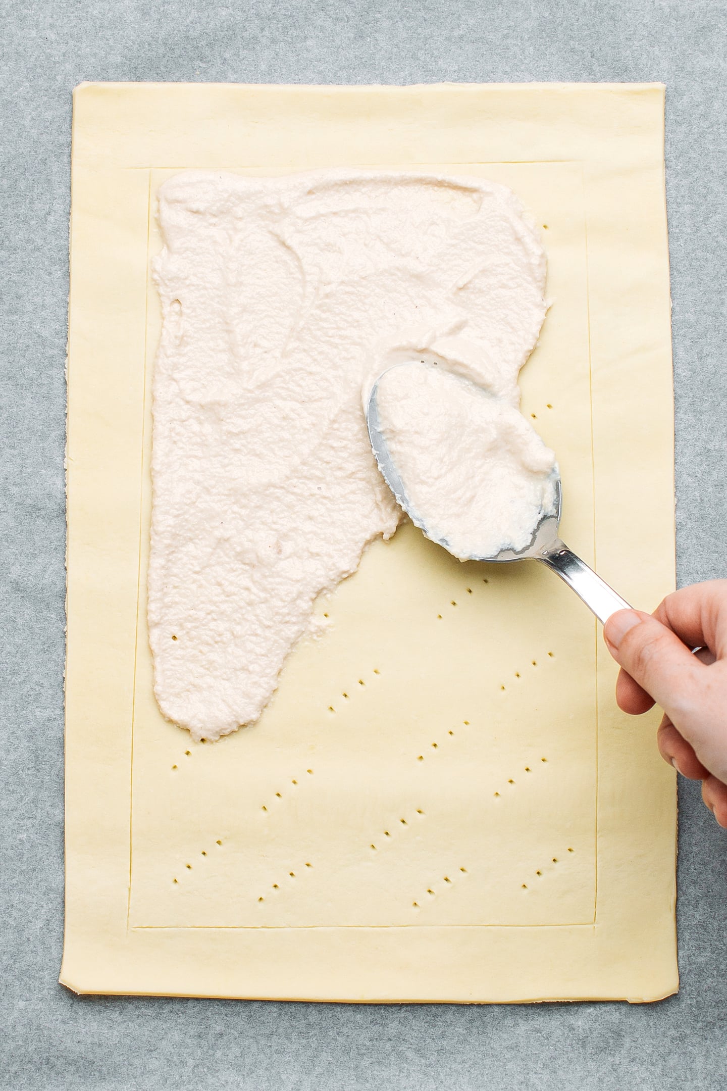 Spreading cashew cheese on top of a puff pastry.