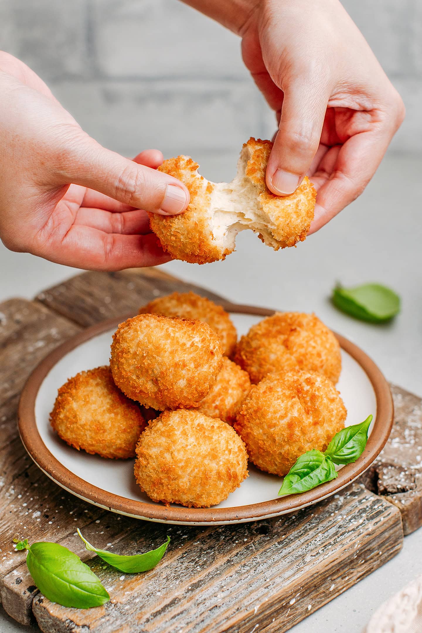 Holding a vegan cheese ball over a plate.