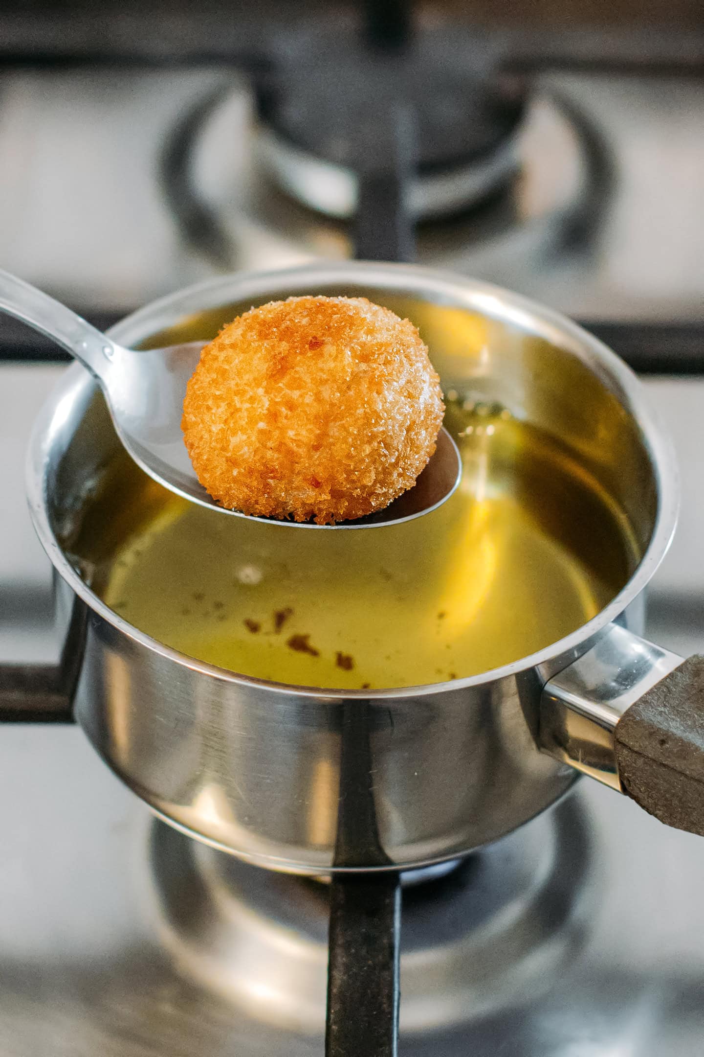 Fried vegan cheese ball on a spoon.