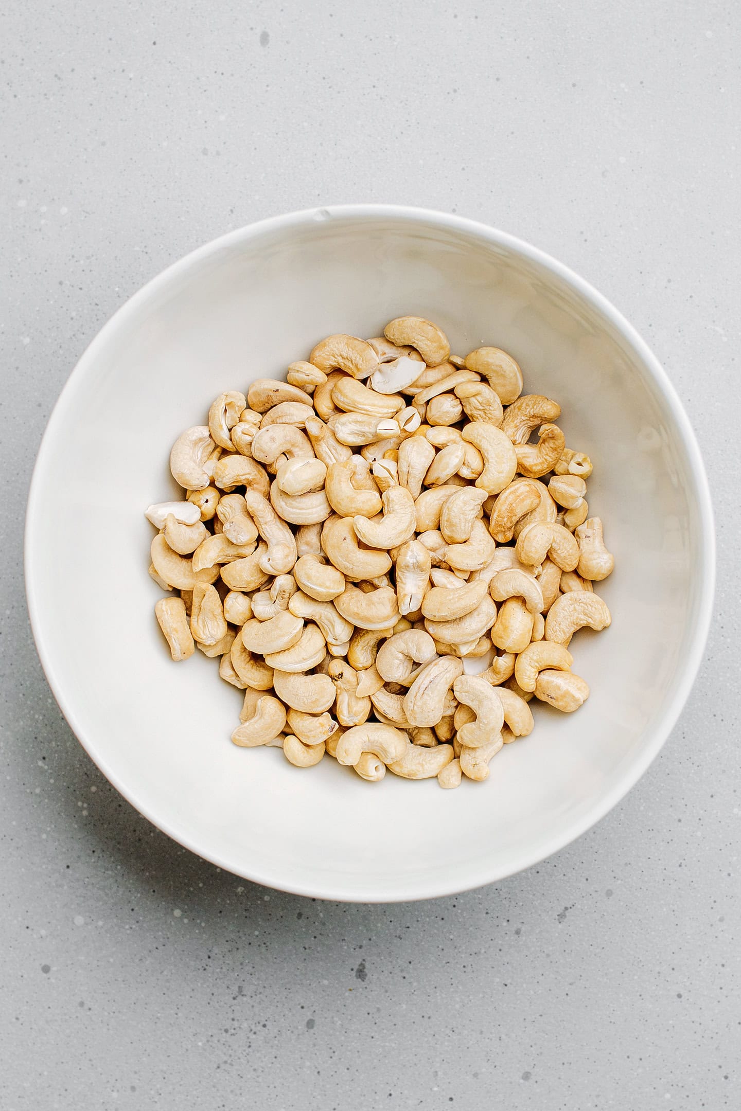 Raw cashews in a mixing bowl.