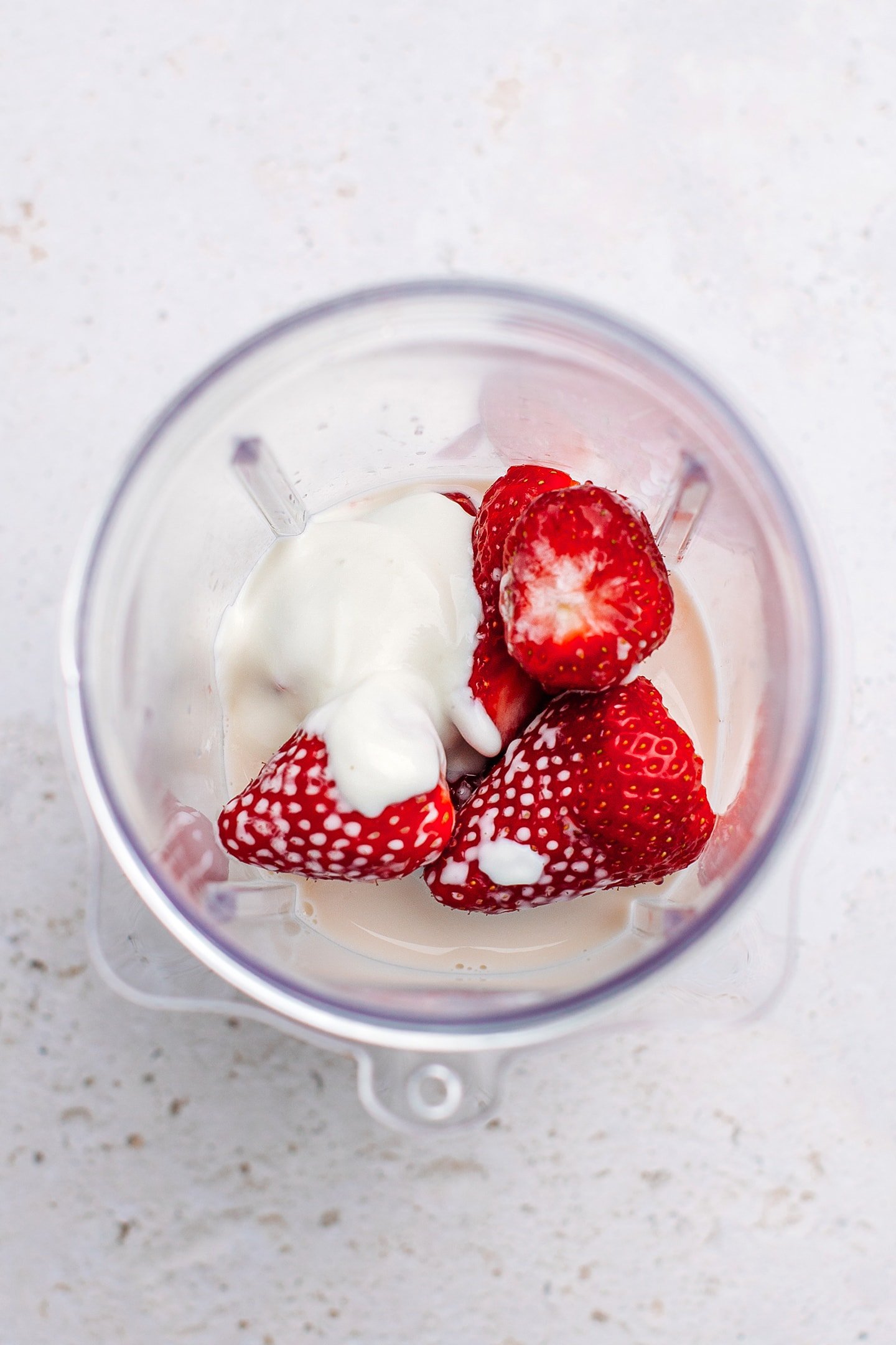 Strawberries, almond milk, and yogurt in a blender.