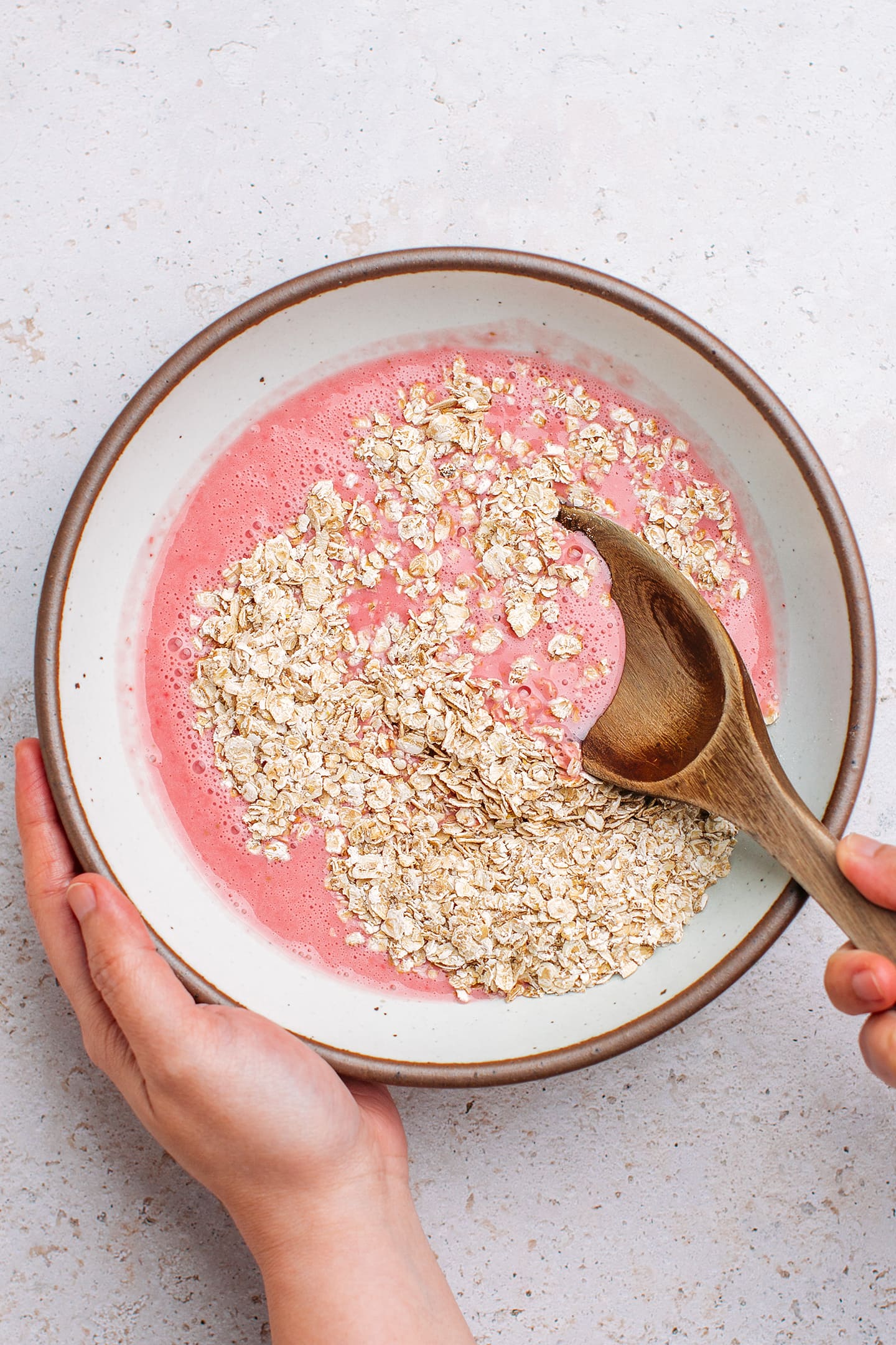 Stirring oats with blended strawberries.