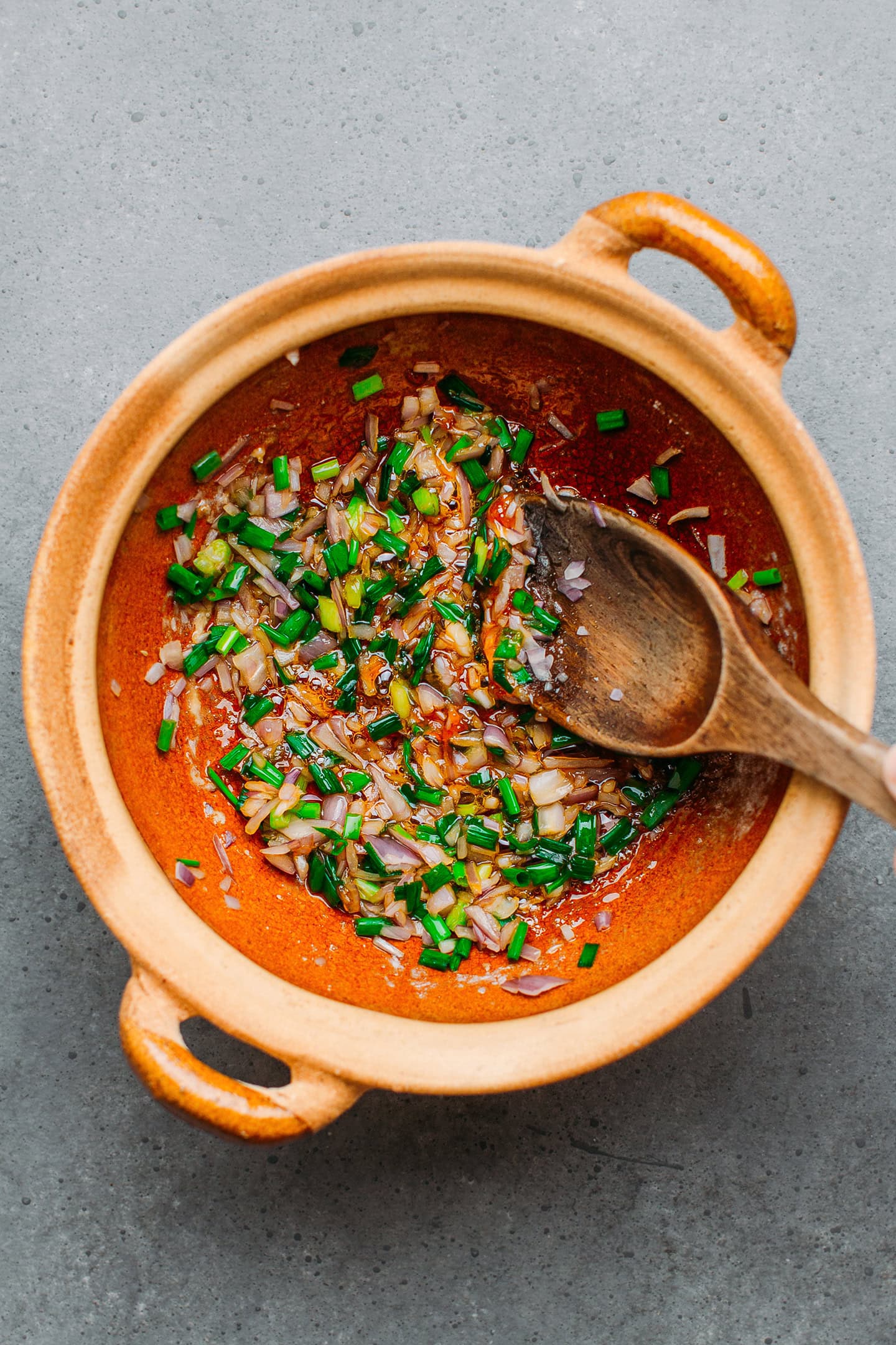 Green onions and shallots in a clay pot.