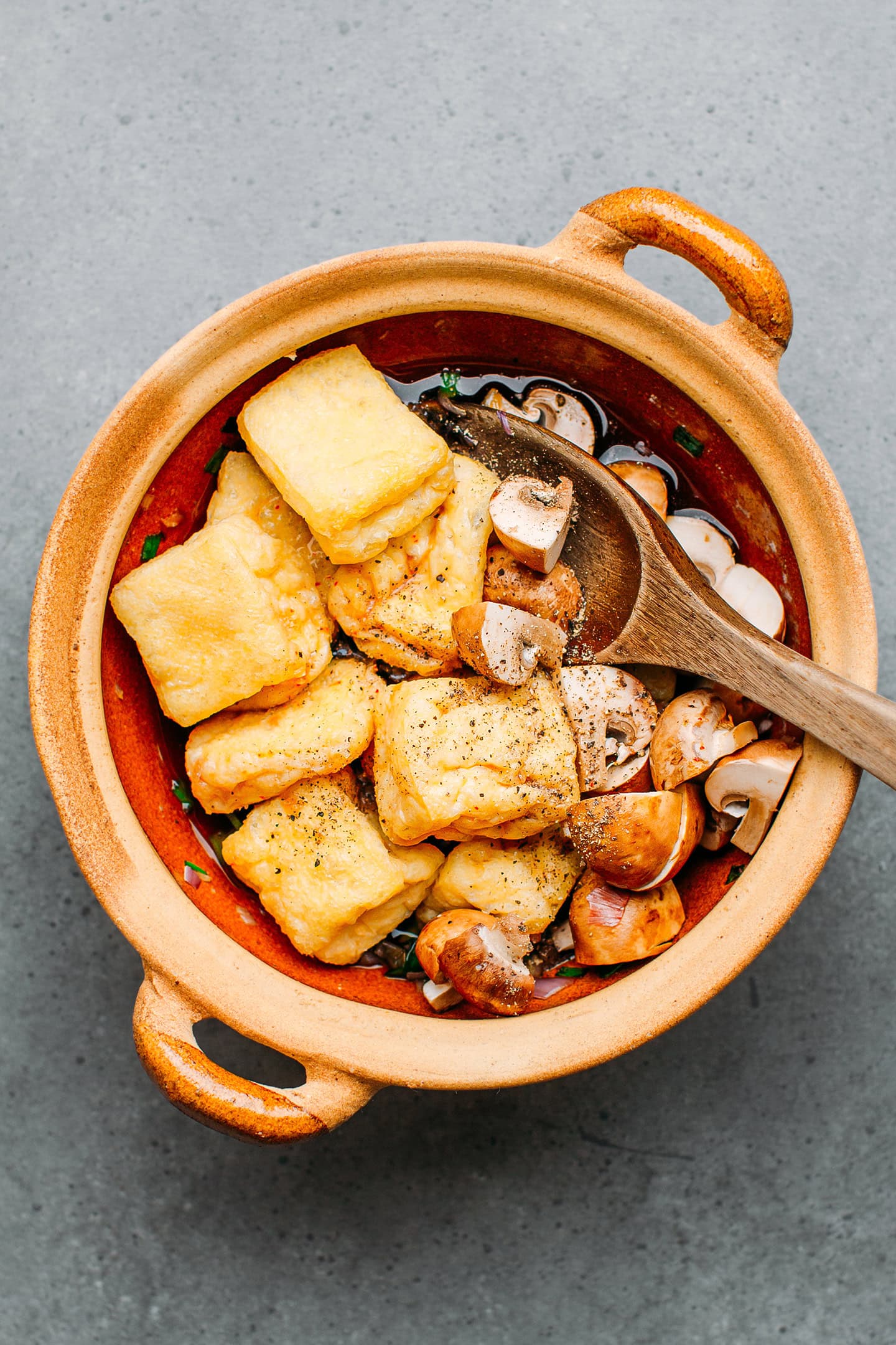 Tofu puffs and mushrooms in a clay pot.