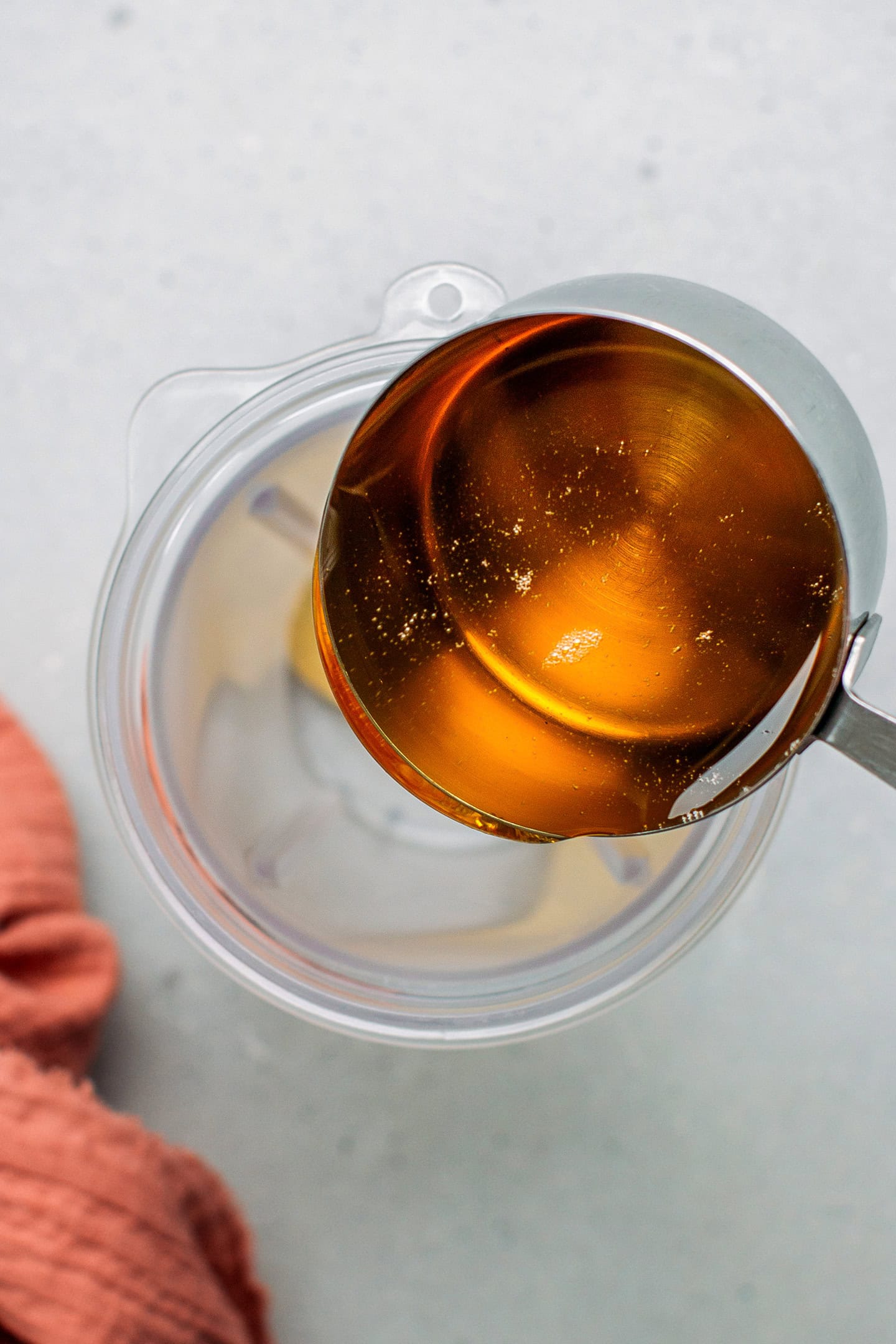 Pouring agave syrup into a blender bowl.