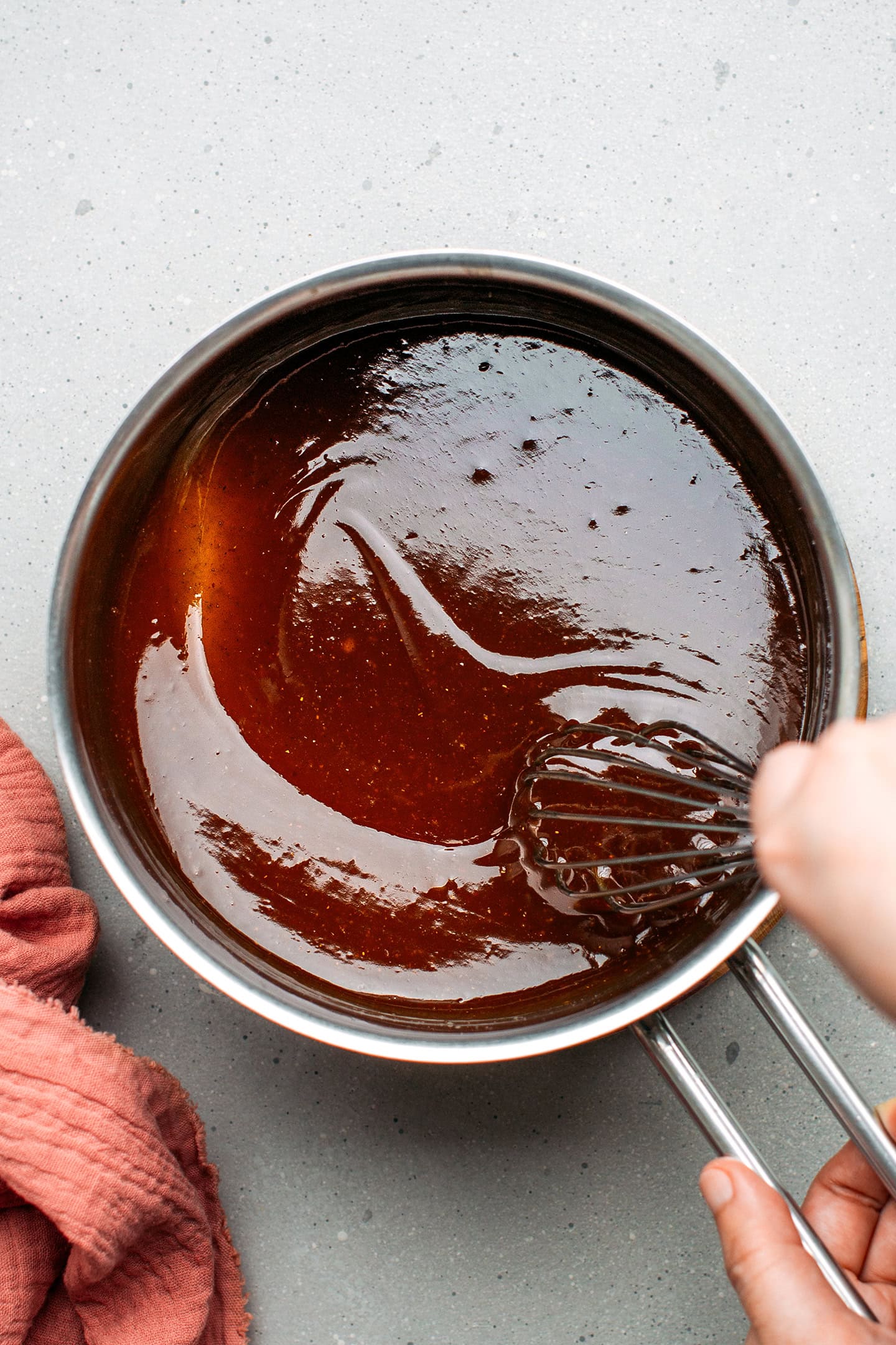 Whisking char siu sauce in a saucepan.