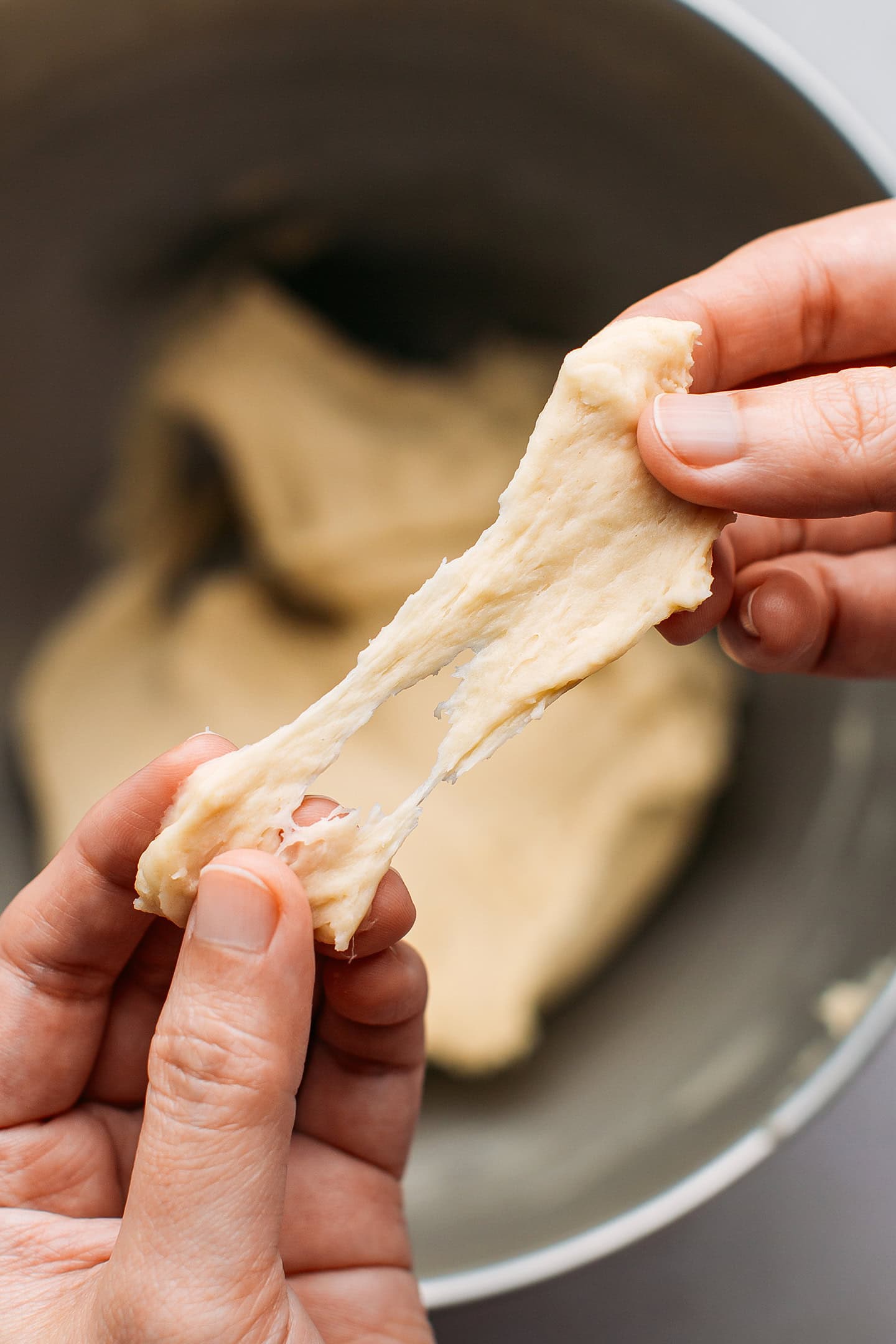 Stretching a piece of dough between fingers.