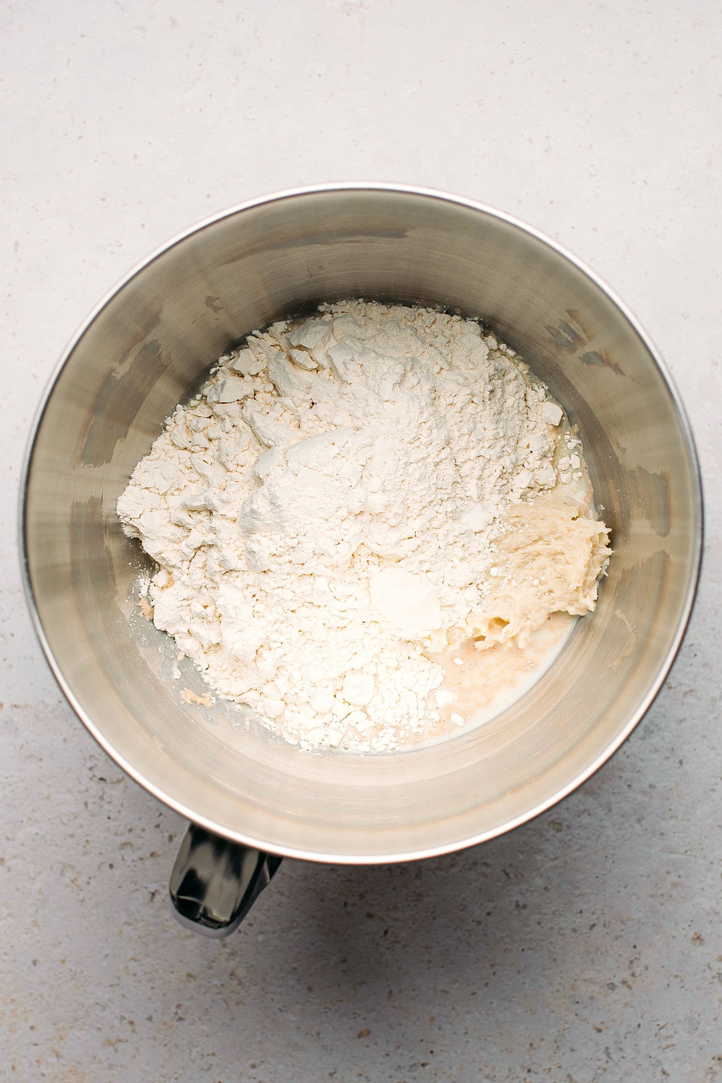 Flour, sugar, and yeast in a stand mixer bowl.