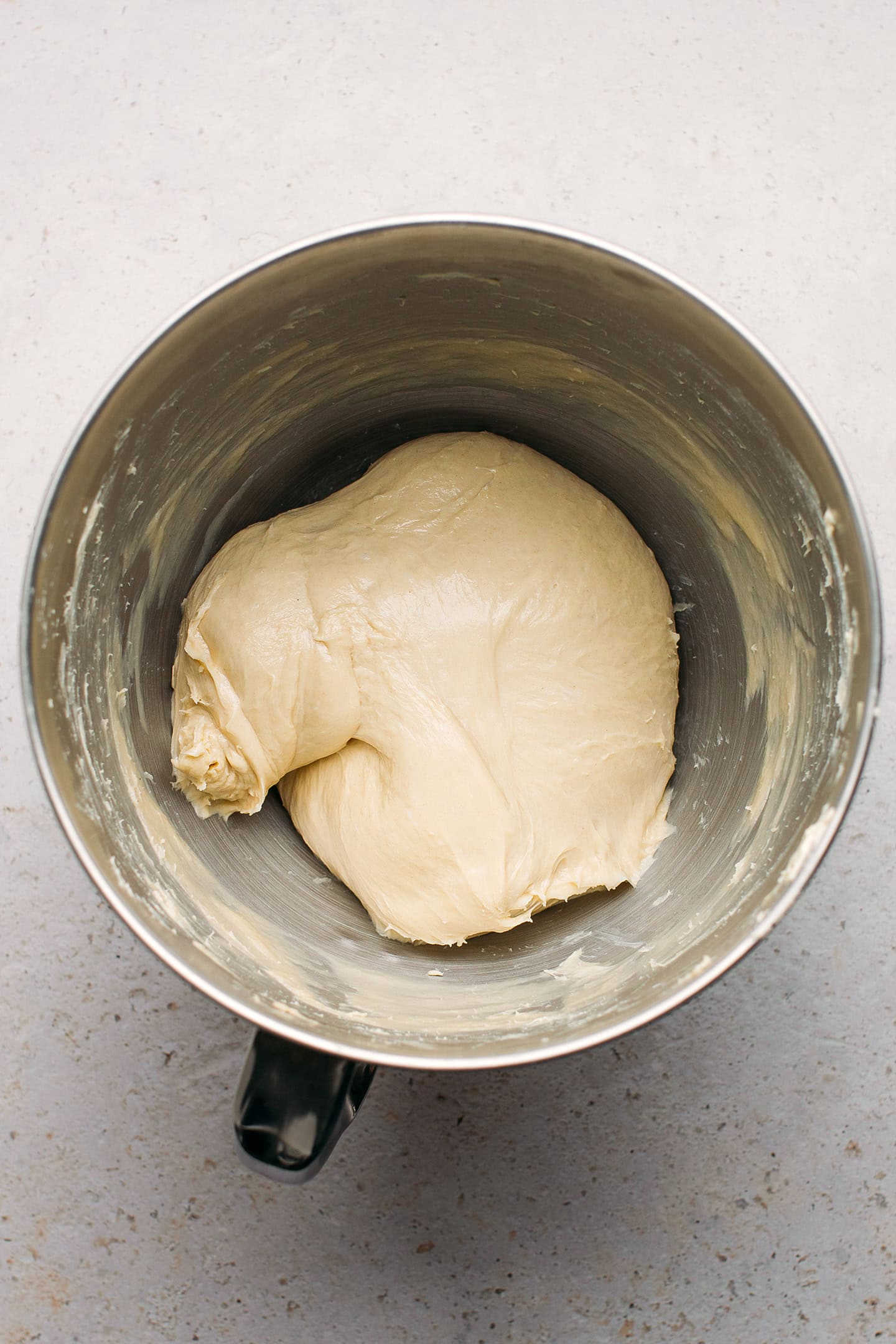 Smooth dough in the bowl of a stand mixer.