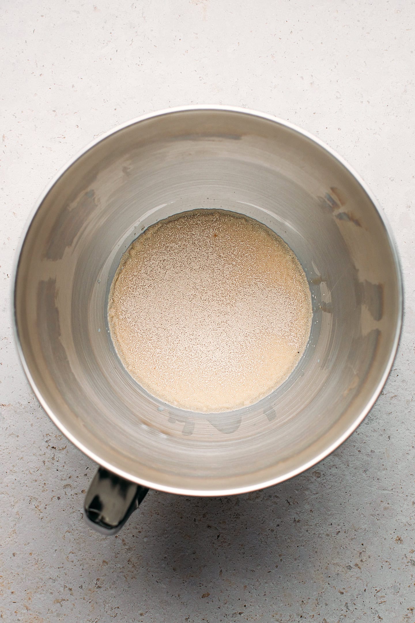 Yeast and milk in the bowl of a stand mixer.