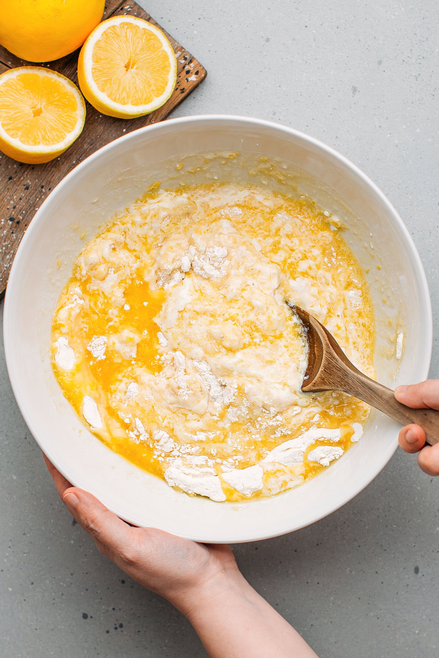 Stirring melted butter with yogurt, flour, and sugar in a mixing bowl.