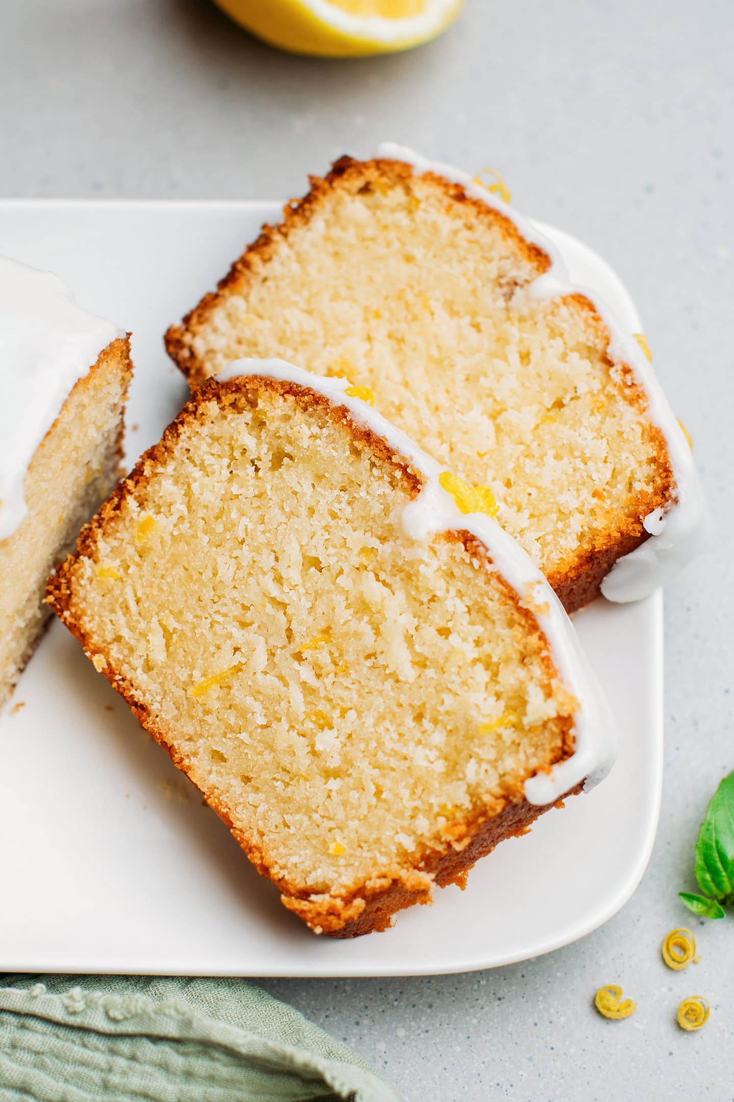 Two slices of glazed lemon cake on a plate.