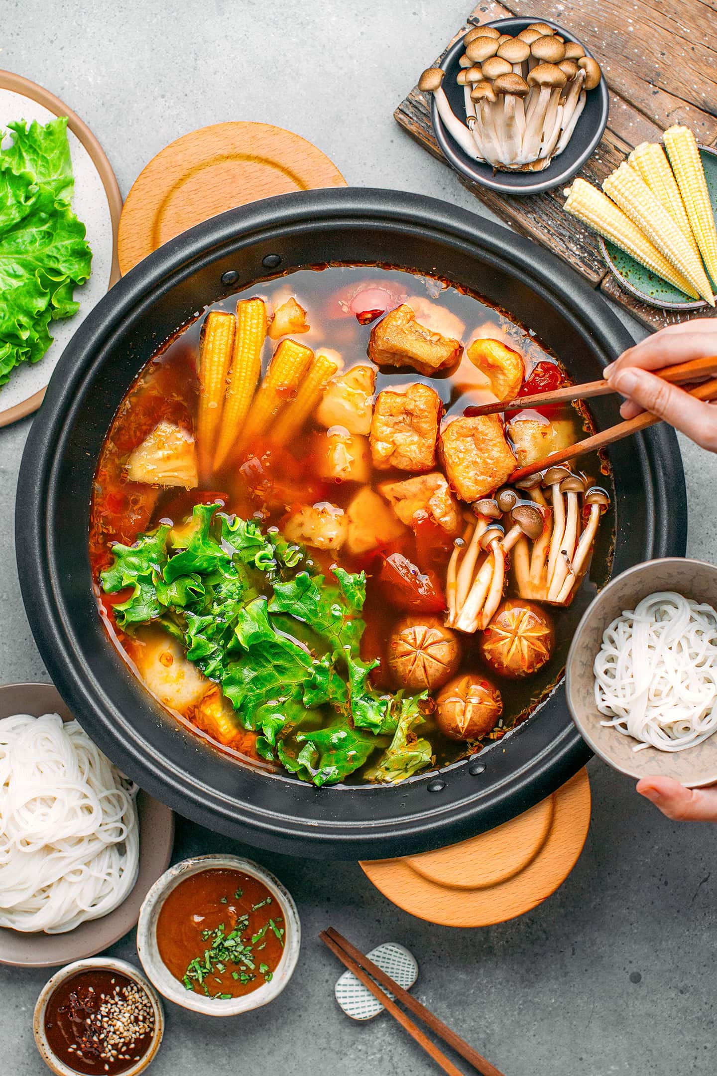 Vegan hot pot filled with baby corn, tofu puffs, mushrooms, and salad.