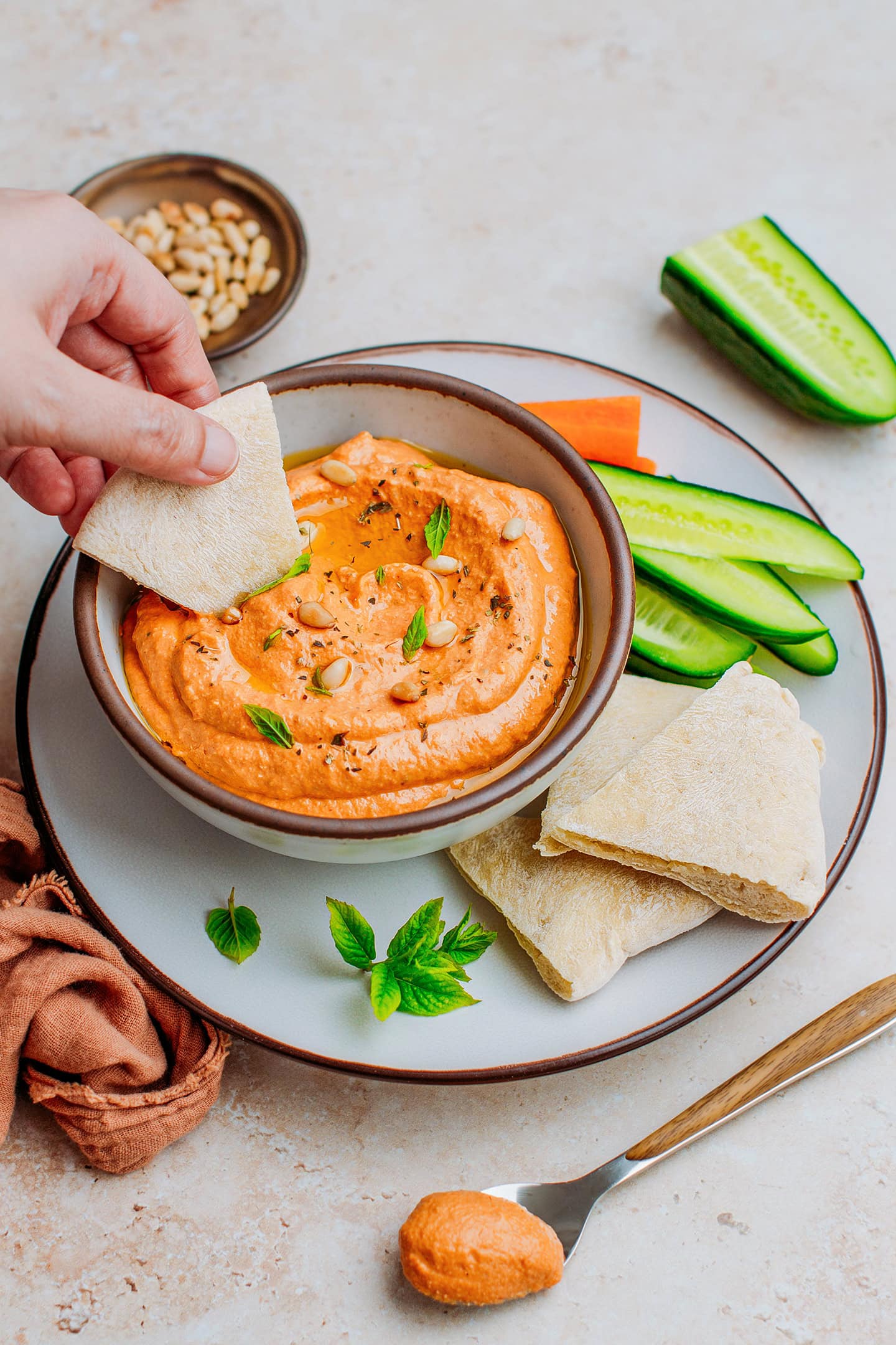 Dipping a piece of pita bread in red bell pepper dip.