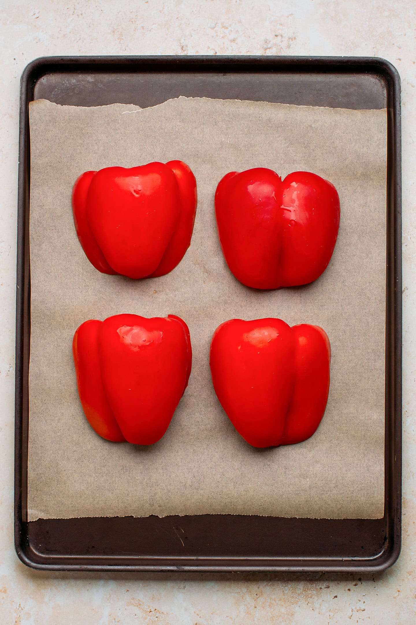 Red bell pepper halves on a baking sheet.