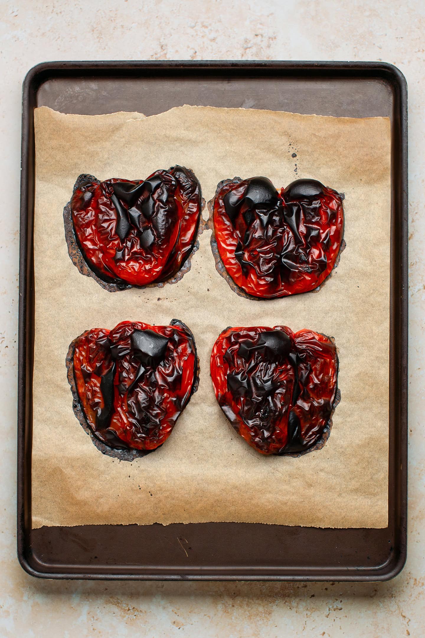 Roasted red bell peppers on a baking sheet.