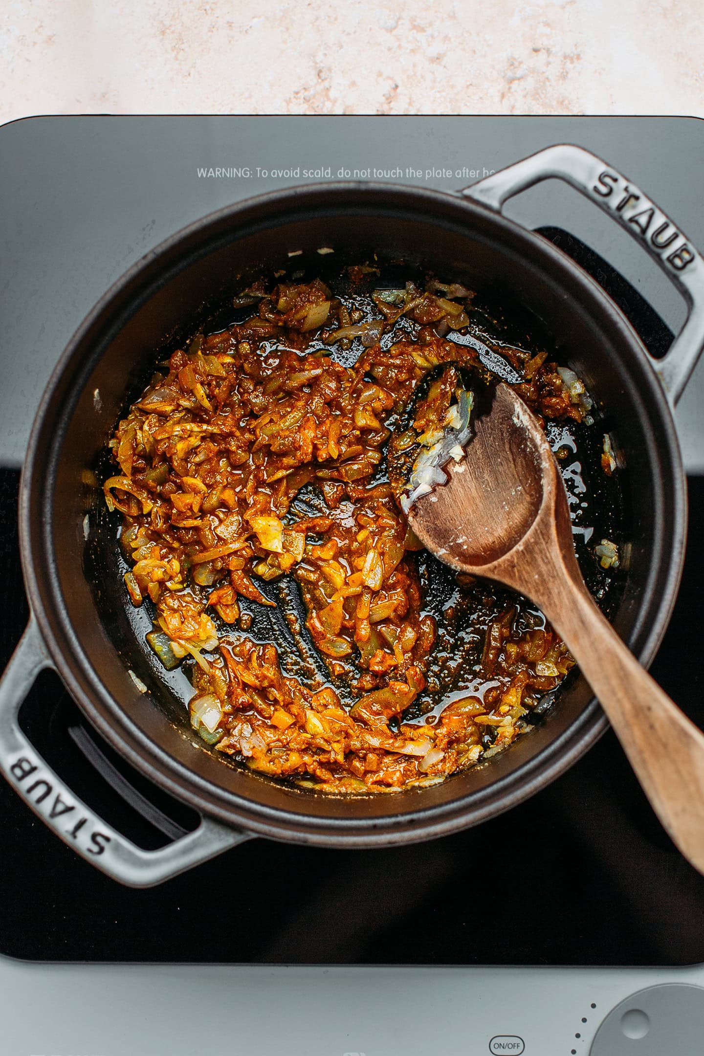 Sautéed onions and garlic with spices in a pot.