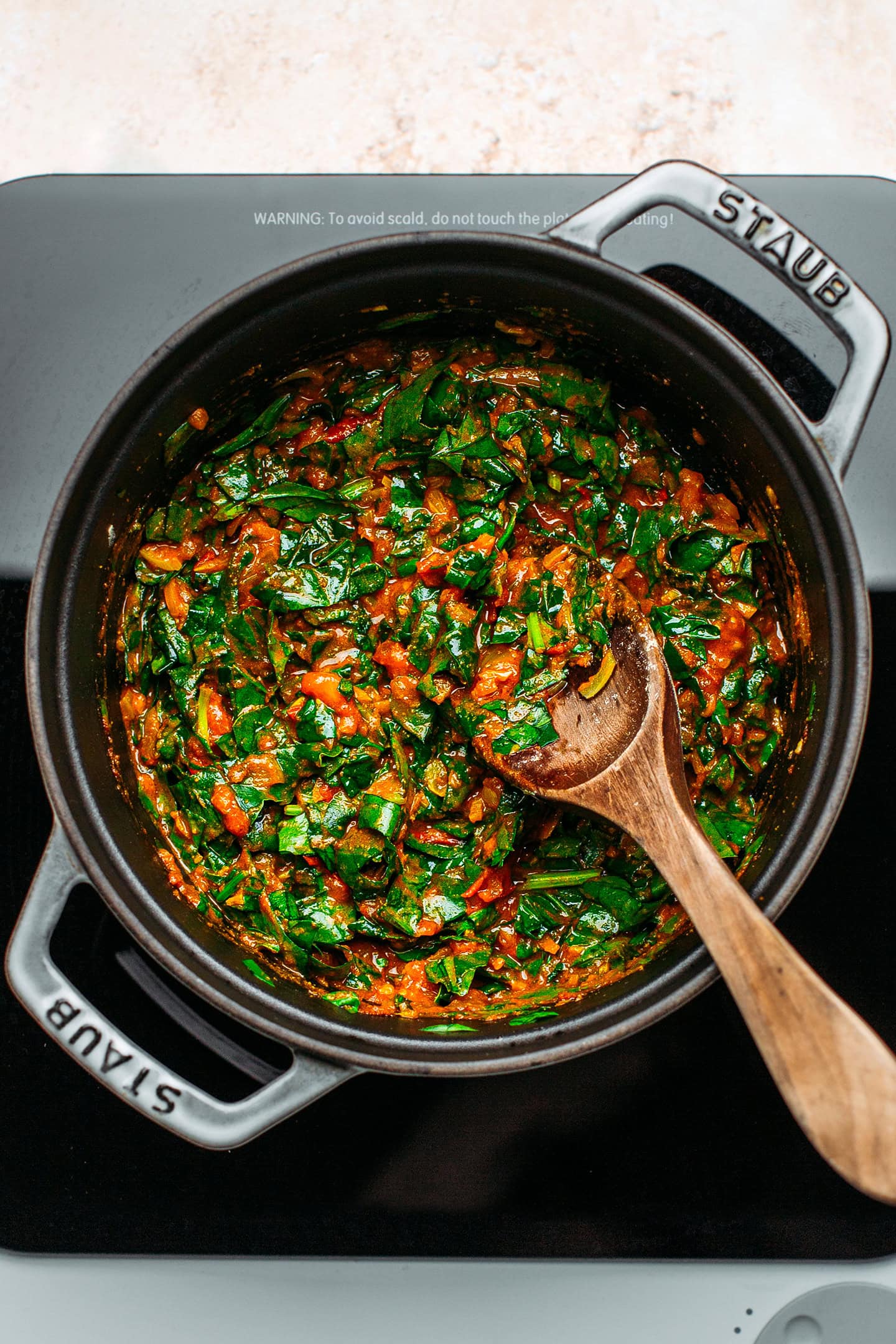 Sautéed tomatoes and spinach in a pot.