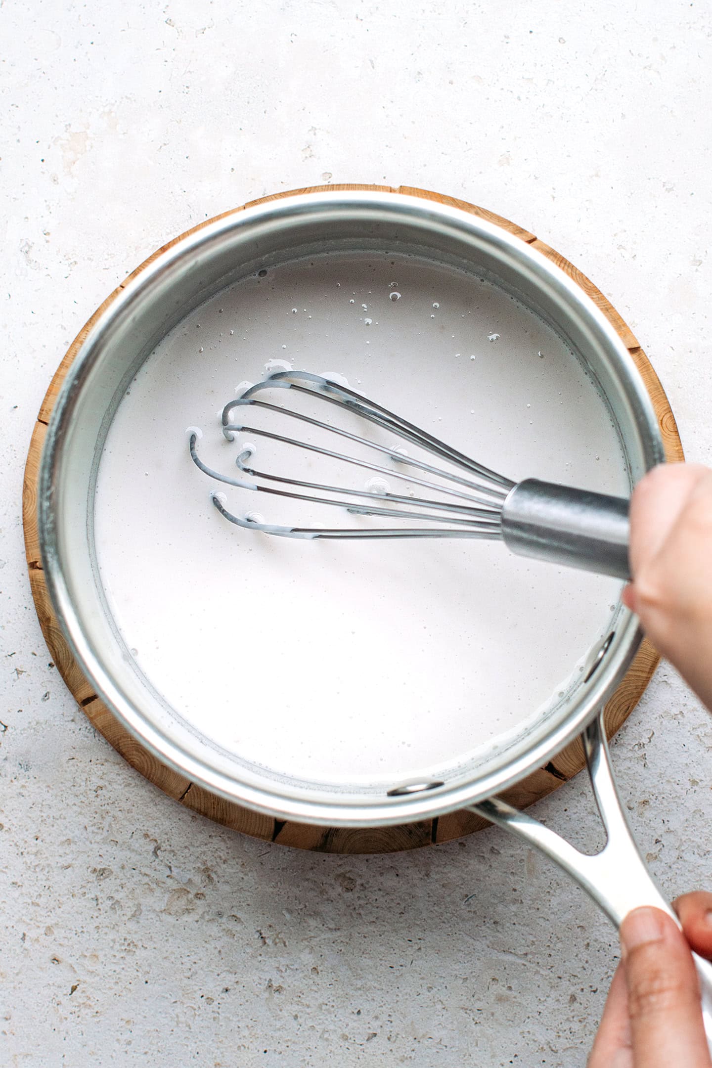 Whisking coconut cream with agar in a saucepan.