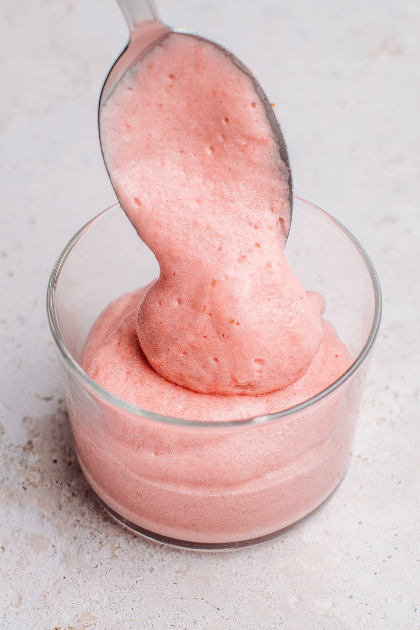 Pouring strawberry mousse into a ramekin.