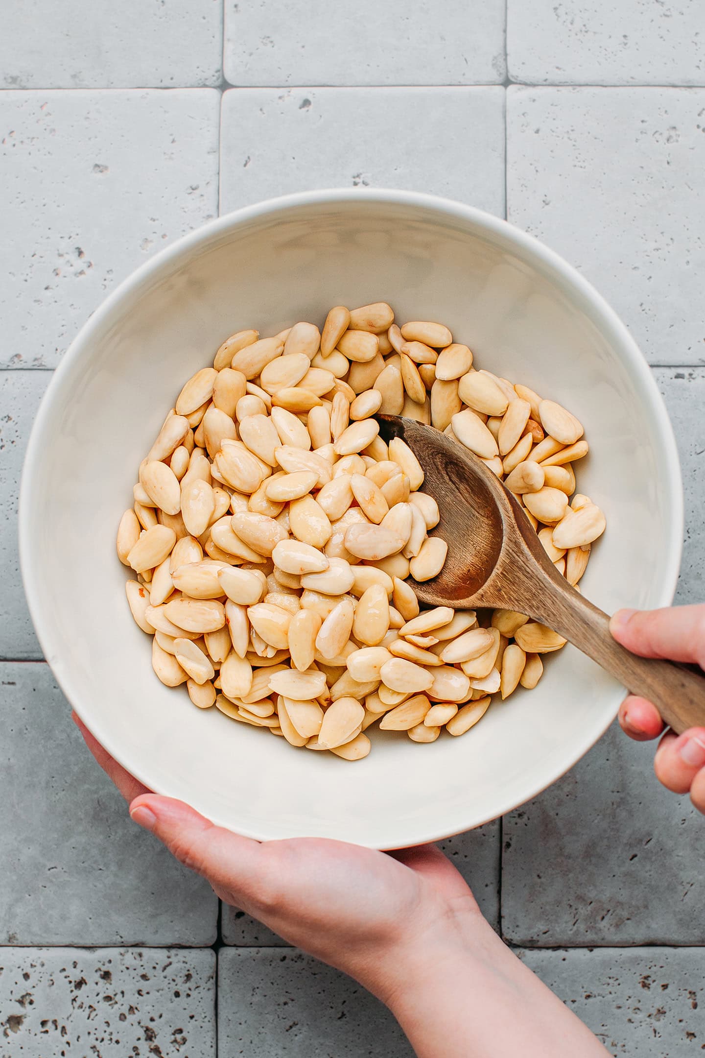 Stirring almonds with syrup in a mixing bowl.