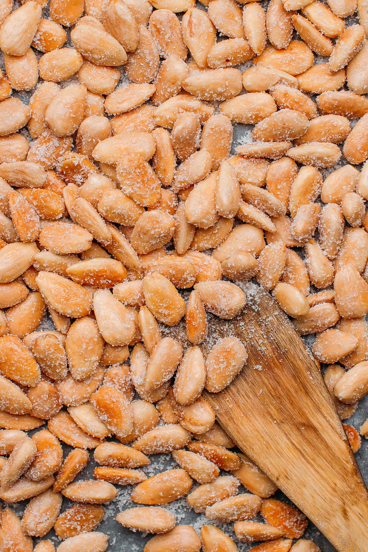 Close-up of roasted almonds tossed with sugar on a baking sheet.