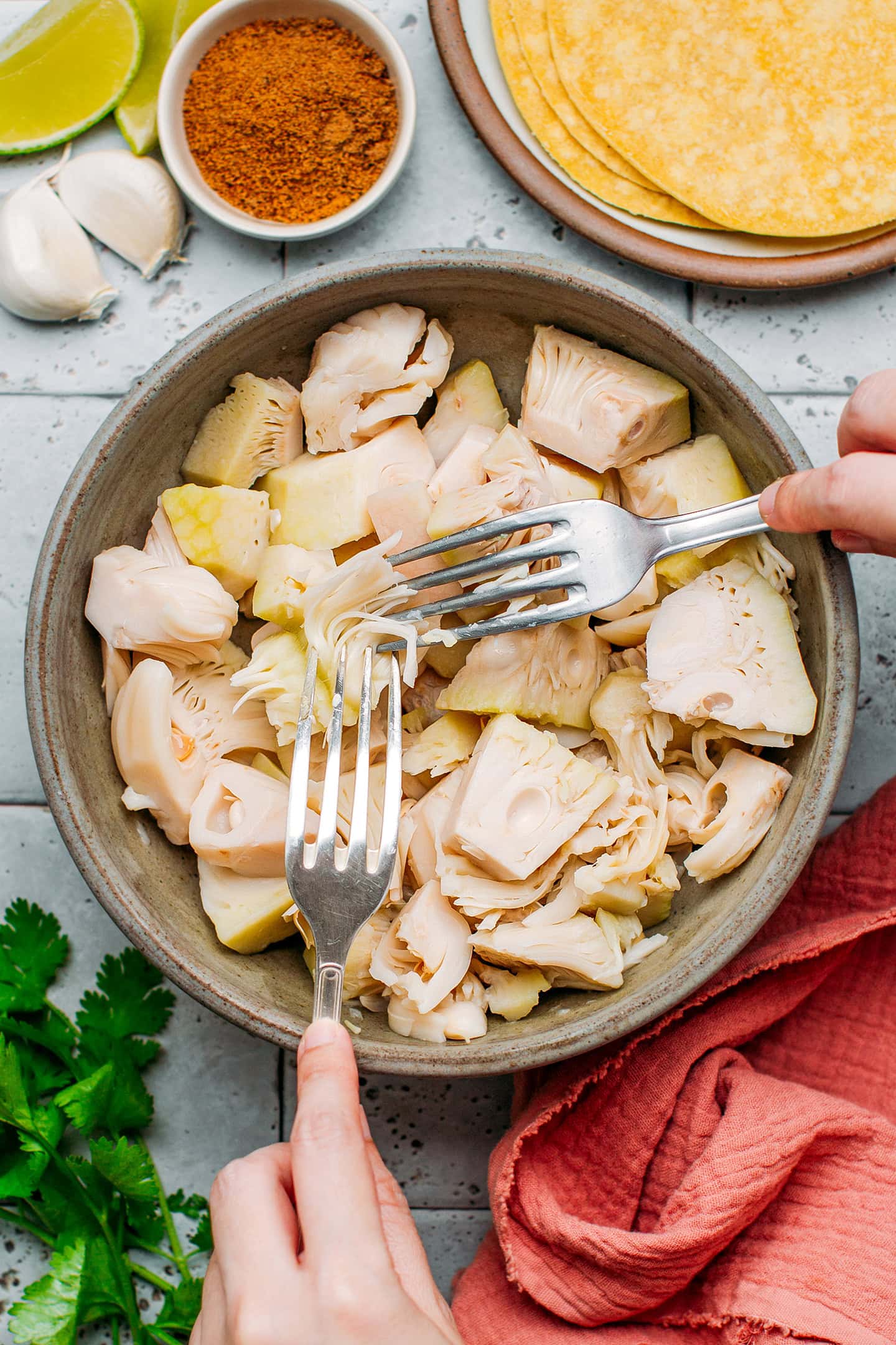 Shredding green jackfruit with two forks.