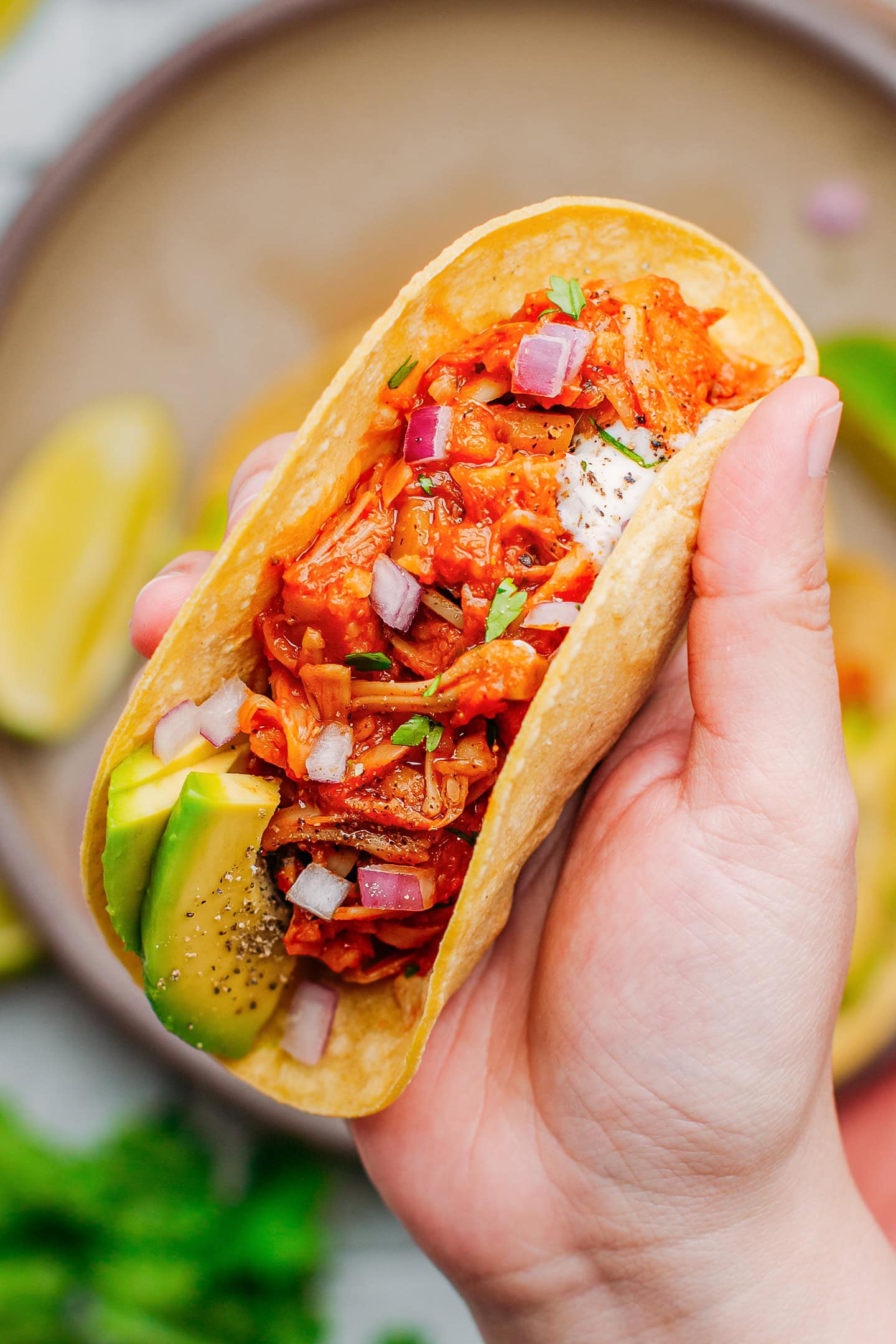 Holding a taco filled with BBQ jackfruit.