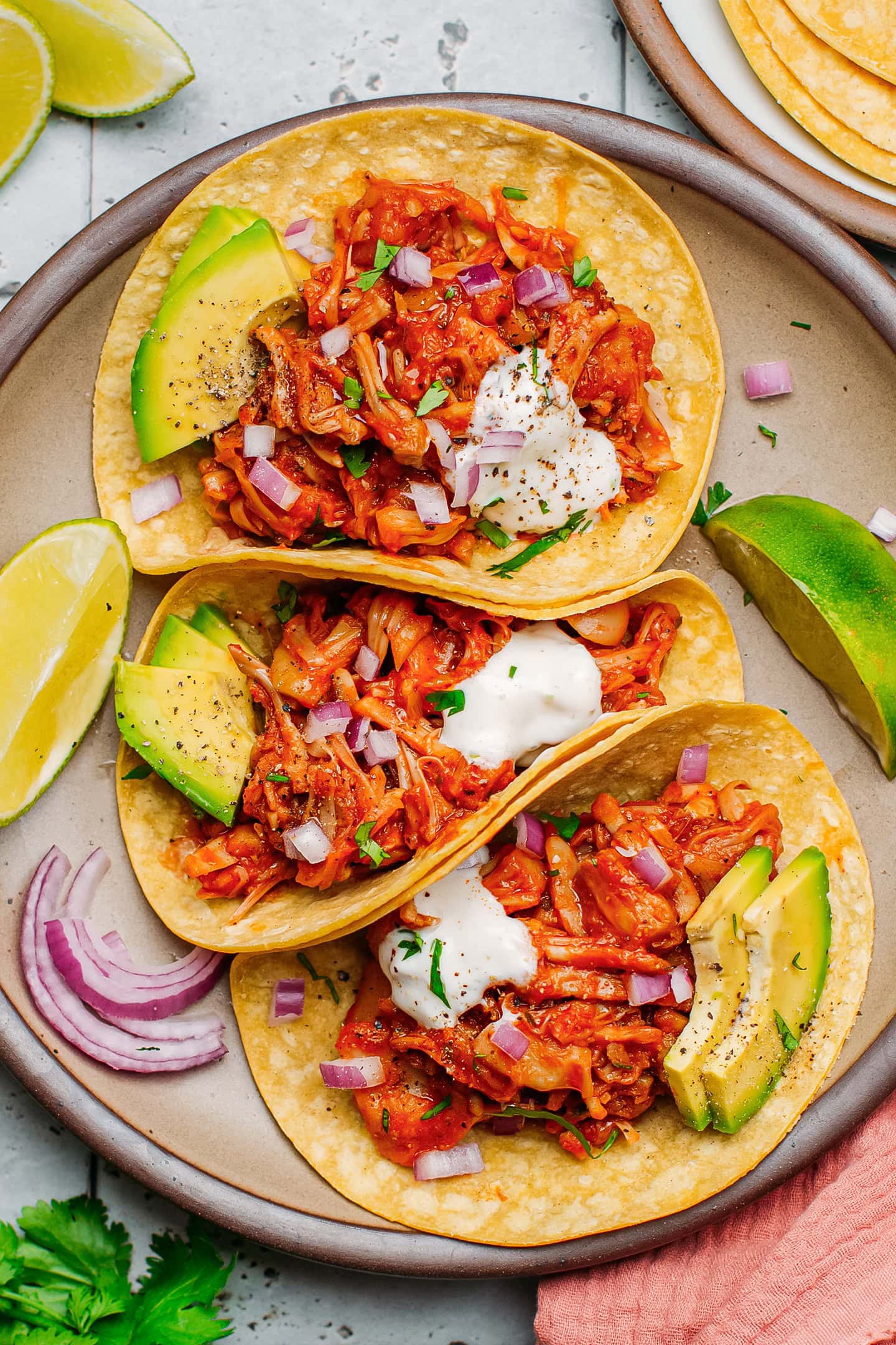 Three tacos filled with pulled jackfruit on a plate.